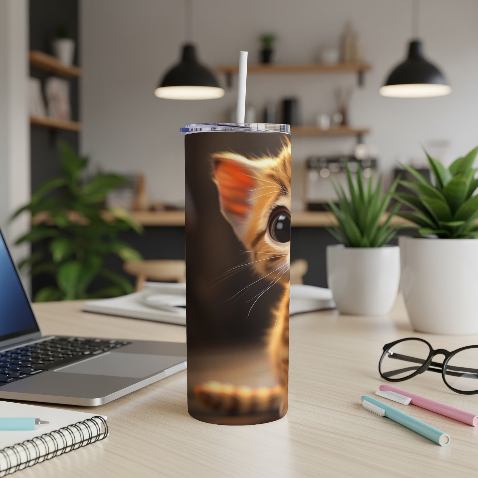 Close-up of a kitten's face on a skinny tumbler with a straw.