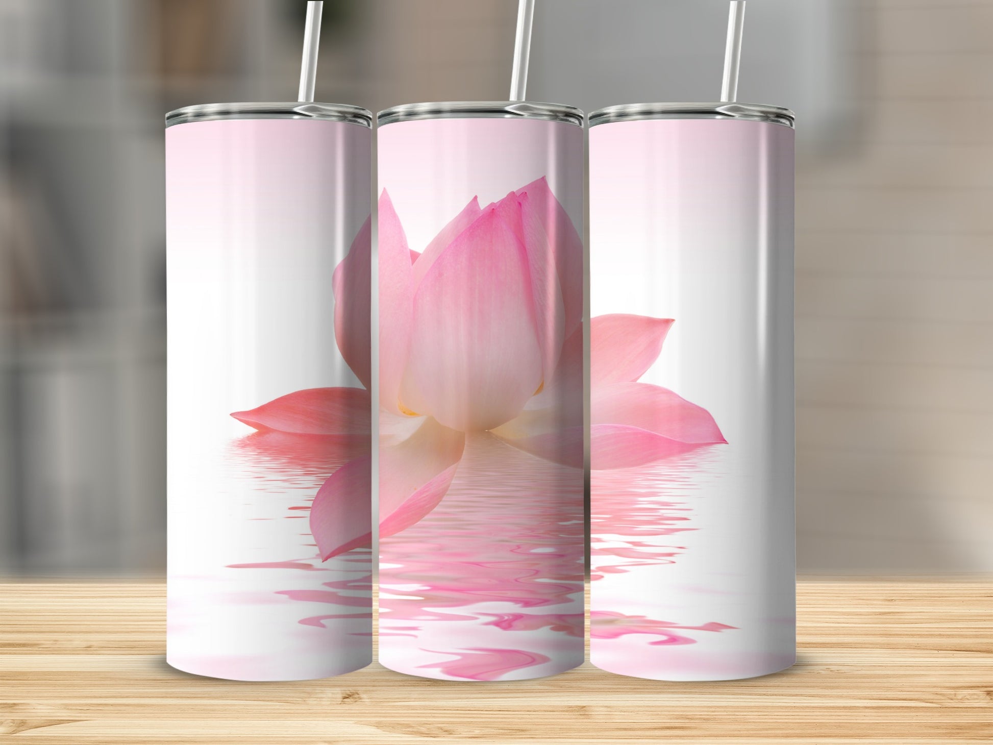 Three tumblers display a pink lotus flower reflected in water.