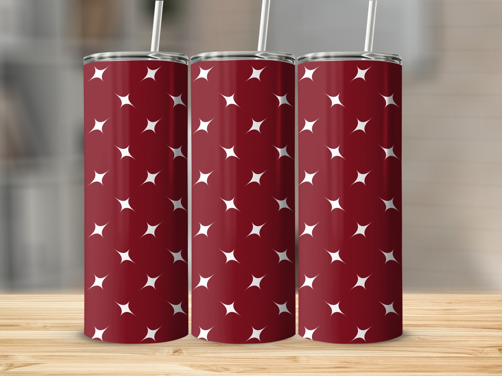 Three dark red tumblers with a white star pattern, each with a white straw.