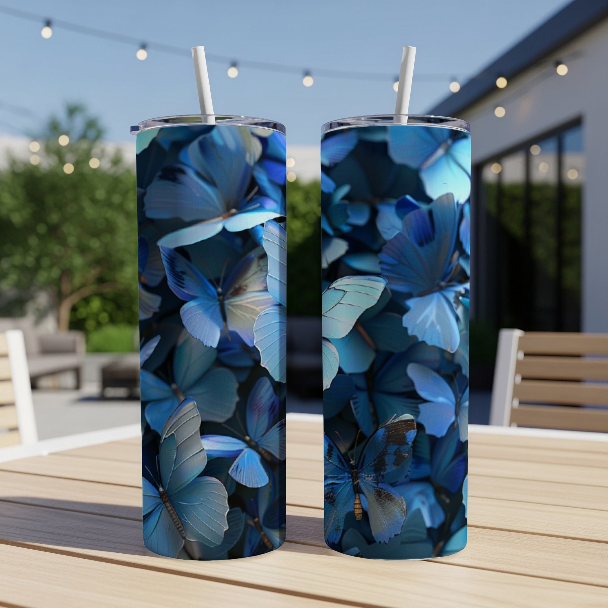 Two blue butterfly tumblers with straws on a wooden table.