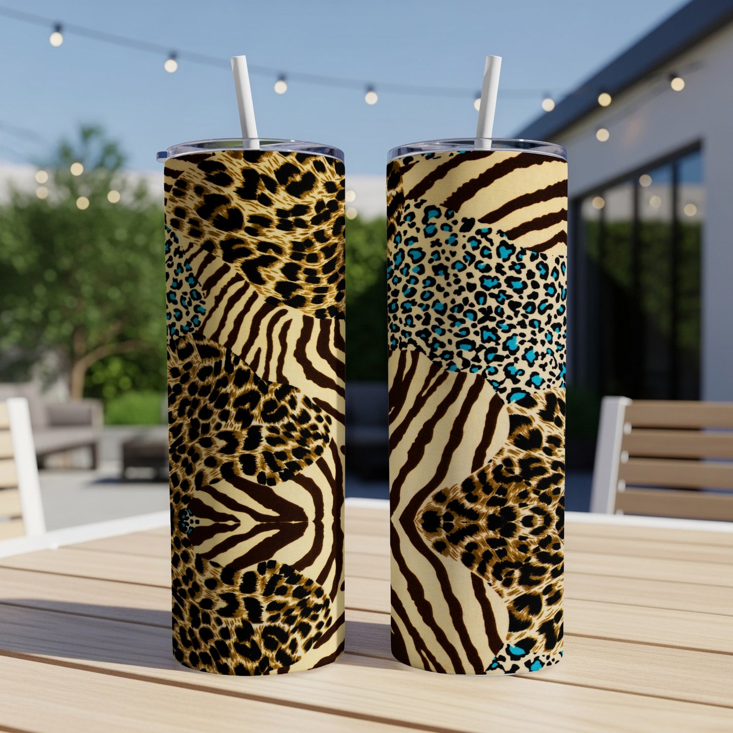 Two animal print tumblers with straws on a wooden table outdoors.