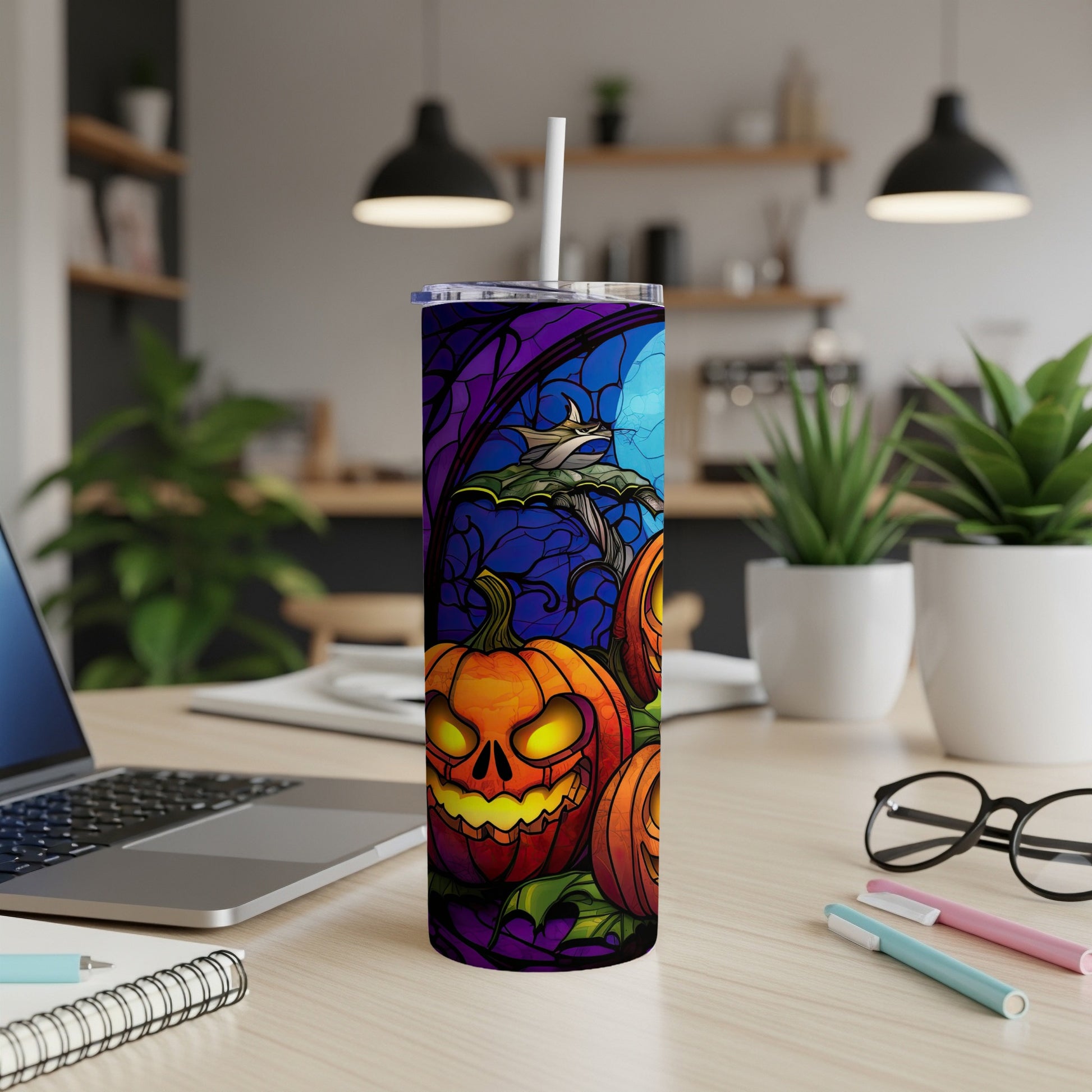 Halloween tumbler with stained-glass pumpkins and bats on a desk.
