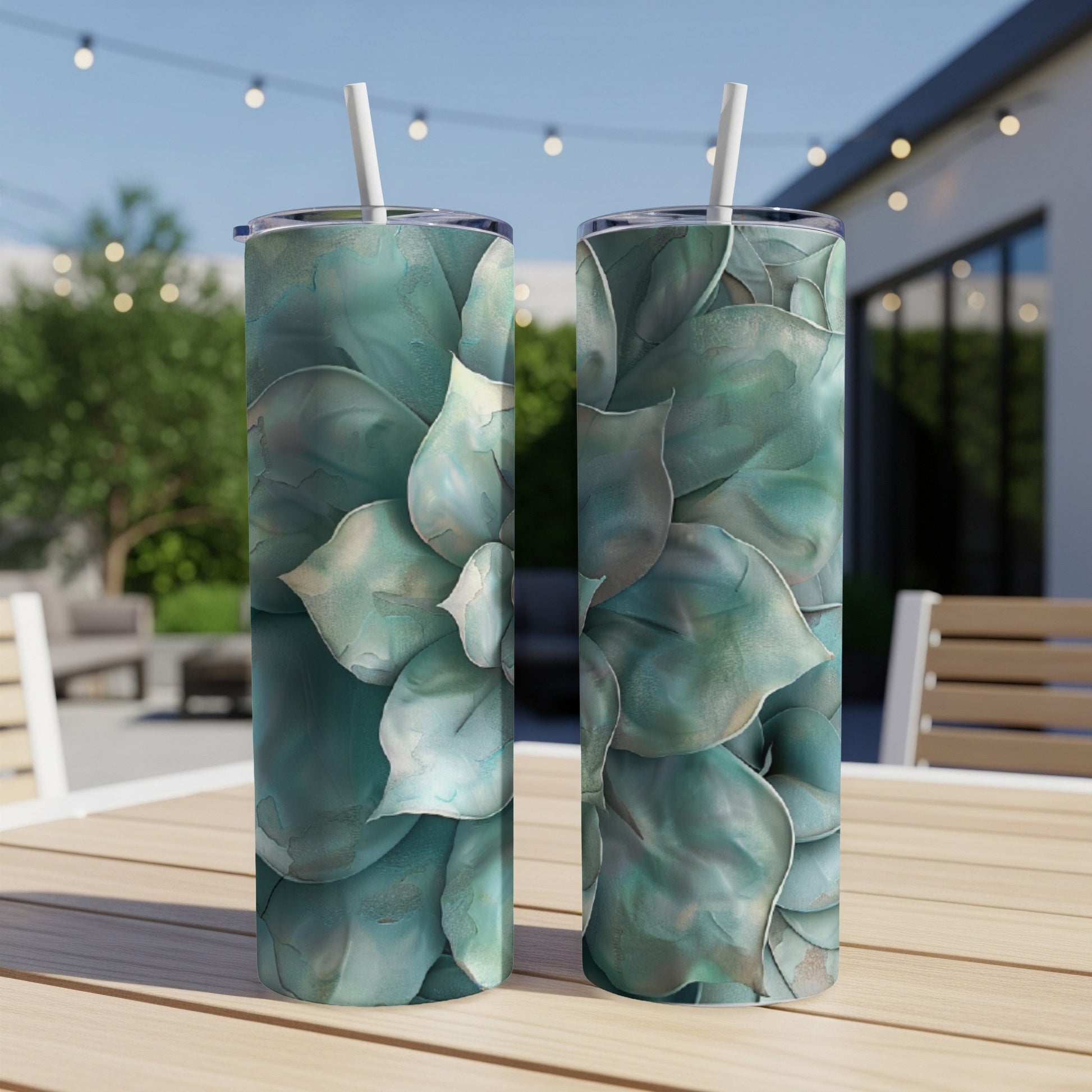 Two tall tumblers with a teal succulent floral design, on a wooden table.