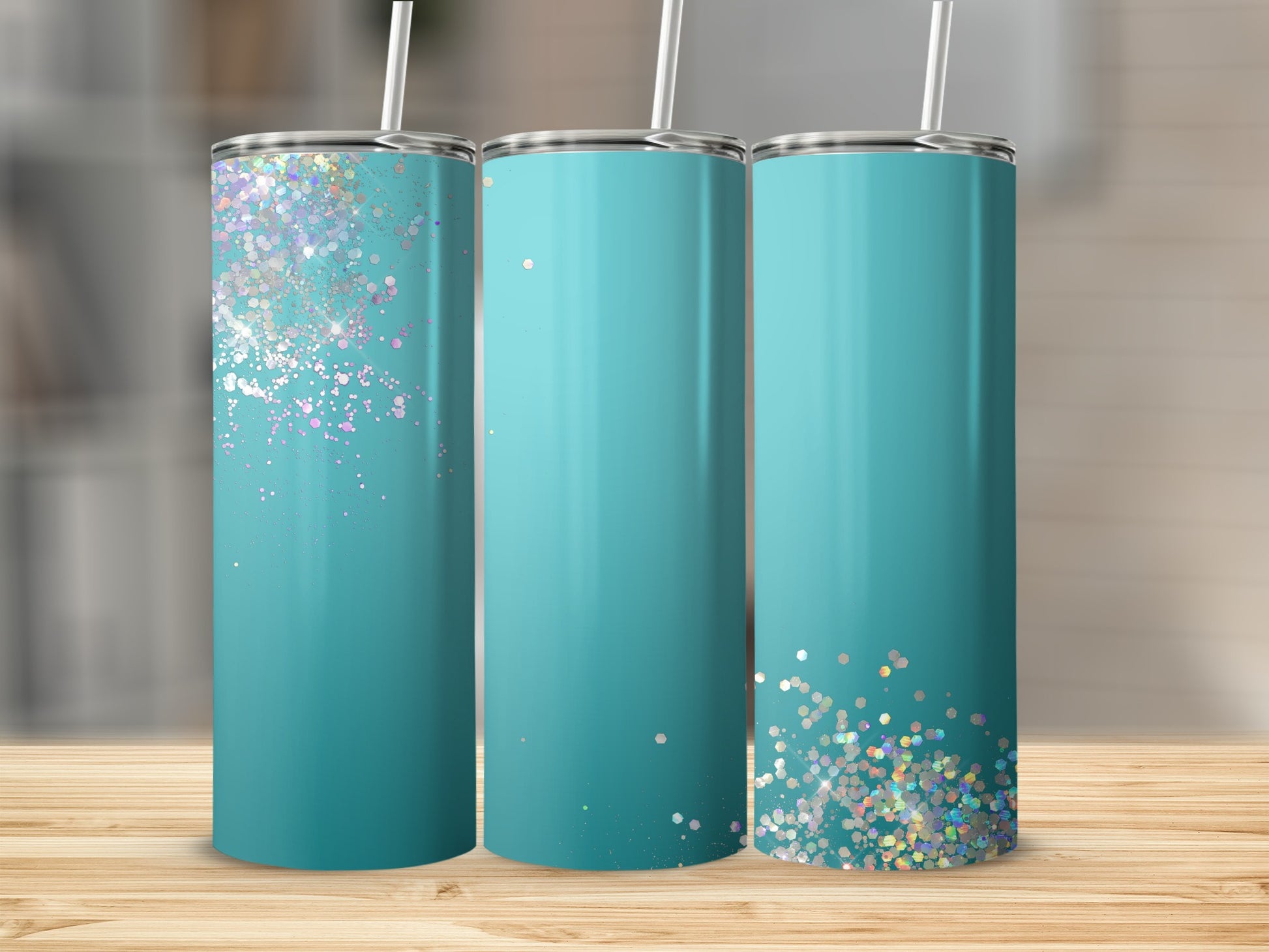 Three teal tumblers with glitter accents are displayed on a wooden surface.