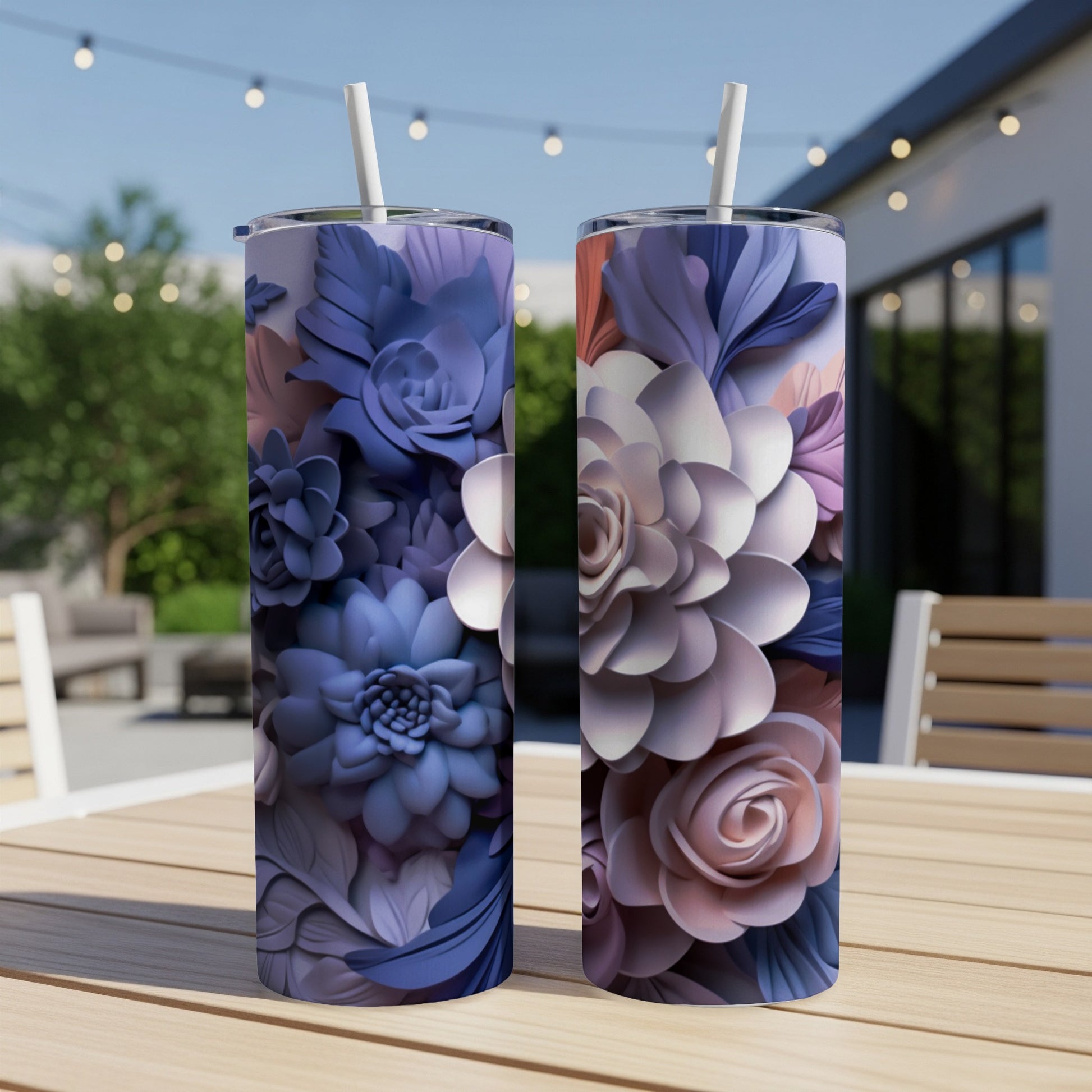 Two tall tumblers with floral designs stand on a wooden table outdoors.