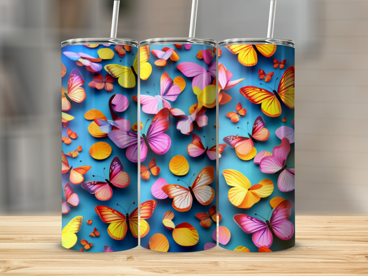 Three tumblers with colorful butterfly designs on a blue background.