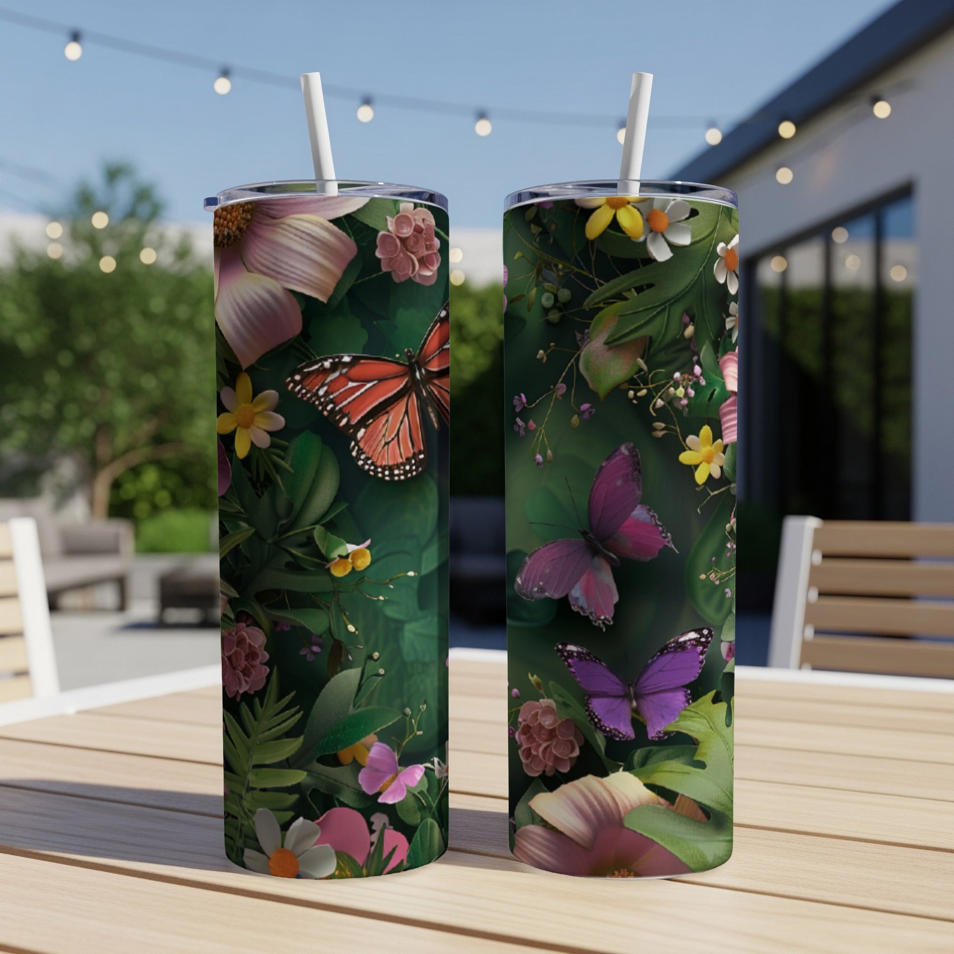 Two tumblers with butterflies and floral designs sit on a table outdoors.
