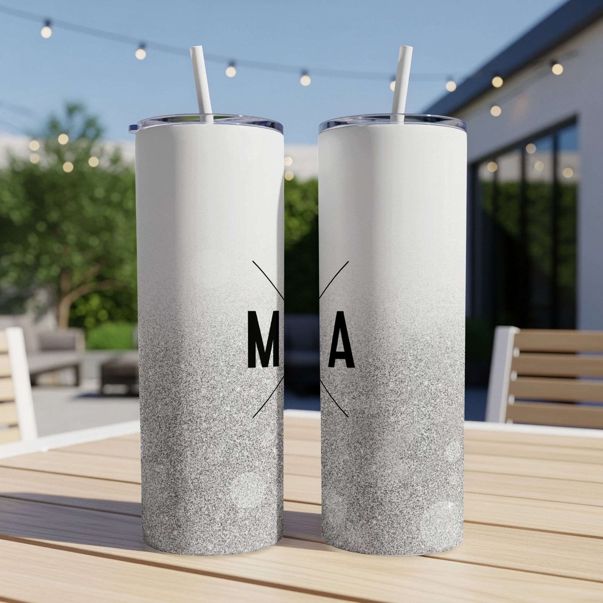 Two tall white tumblers with silver glitter gradient, one with "M" and one with "A".