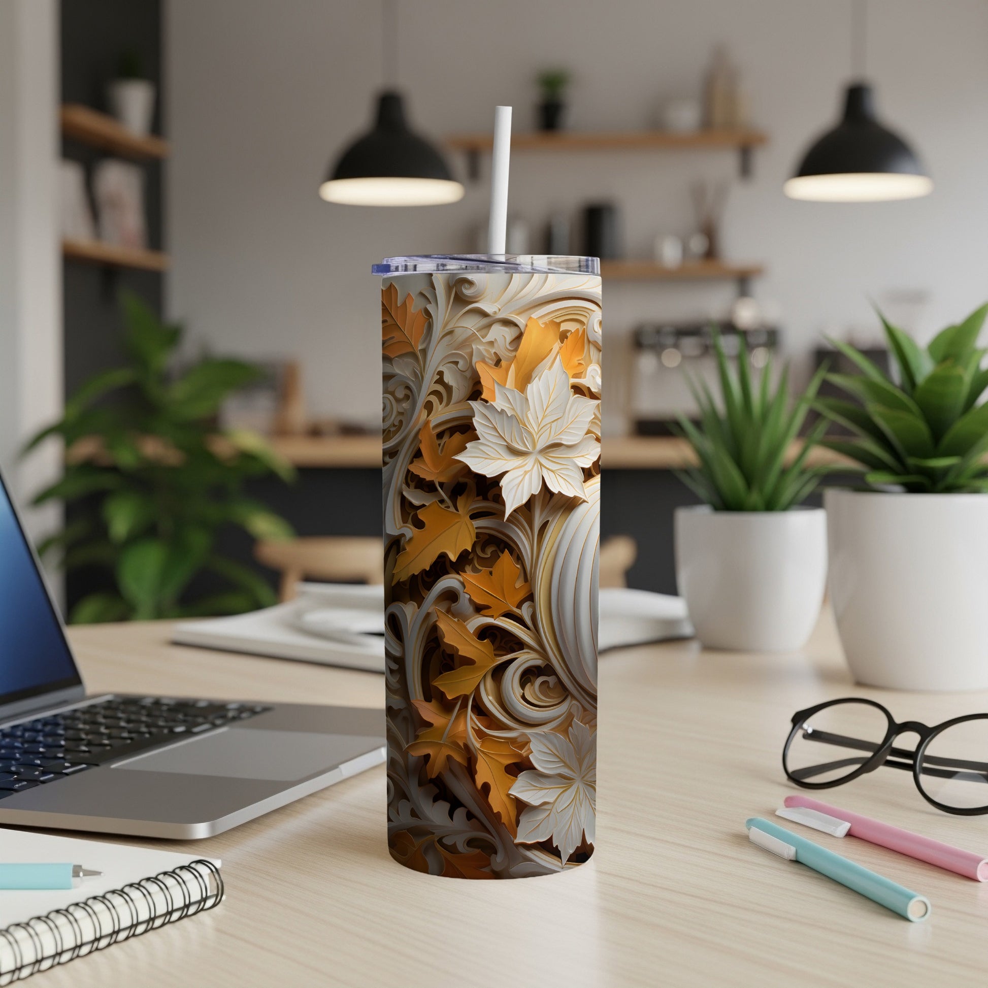 Textured tumbler with fall leaf pattern and straw on a desk.