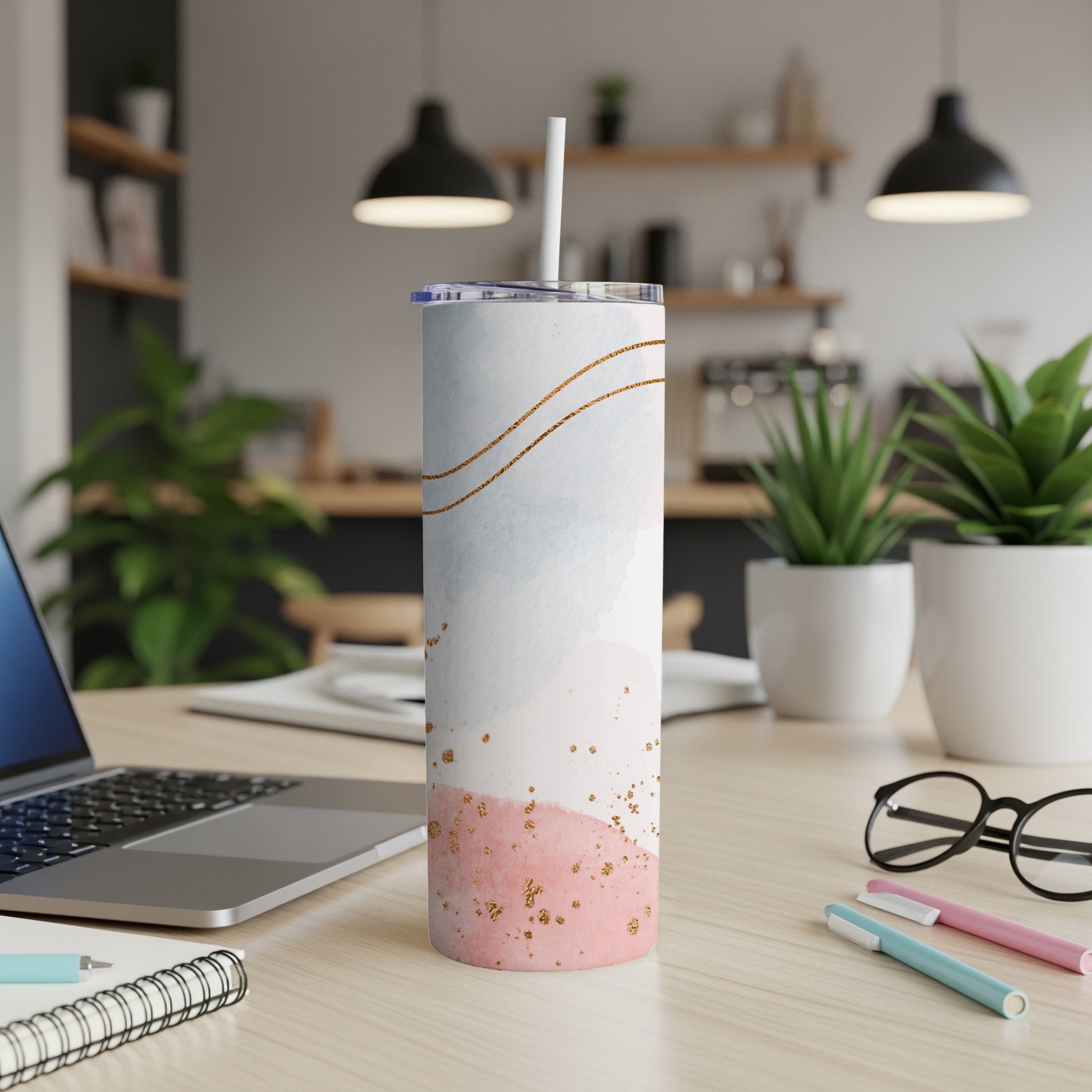 White, blue, and pink watercolor tumbler with gold accents, on a desk.
