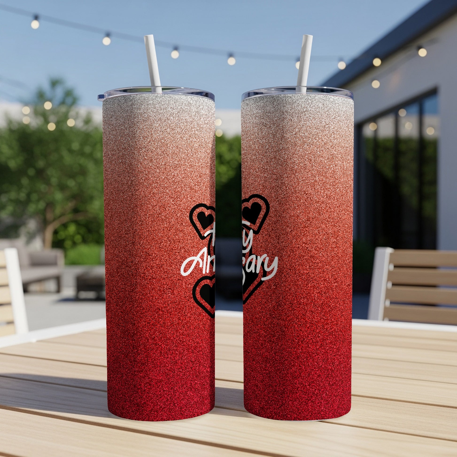 Two glitter tumblers with "Happy Anniversary" text on a table.