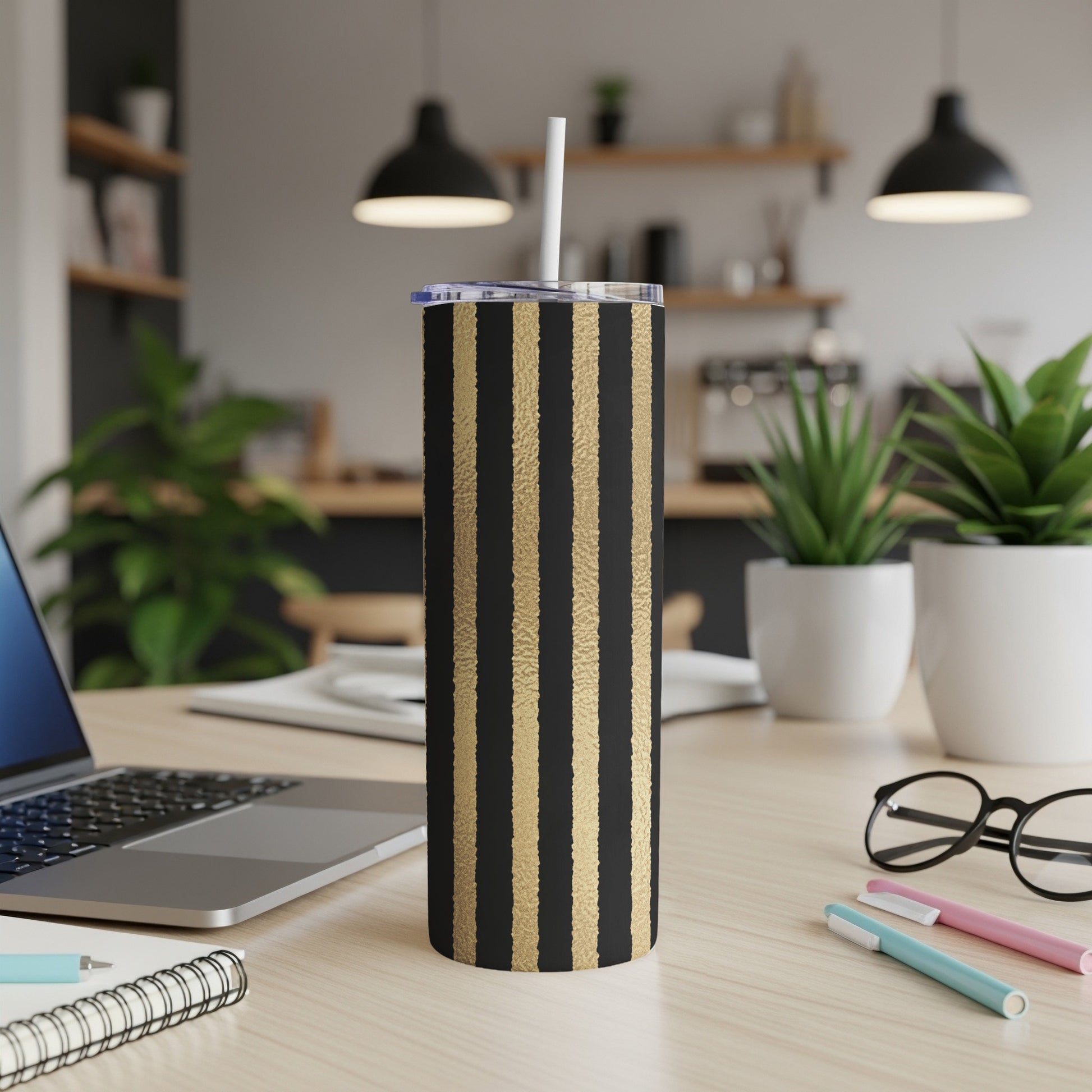 Black tumbler with gold vertical stripes and a white straw.
