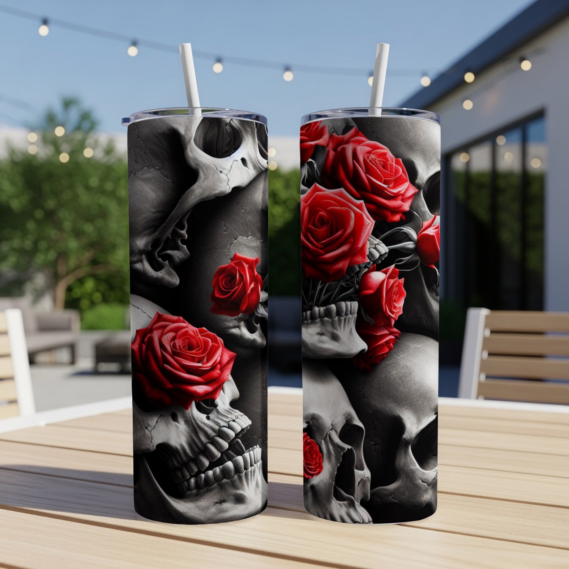 Two tumblers with skull and red rose designs sit on a table outdoors.