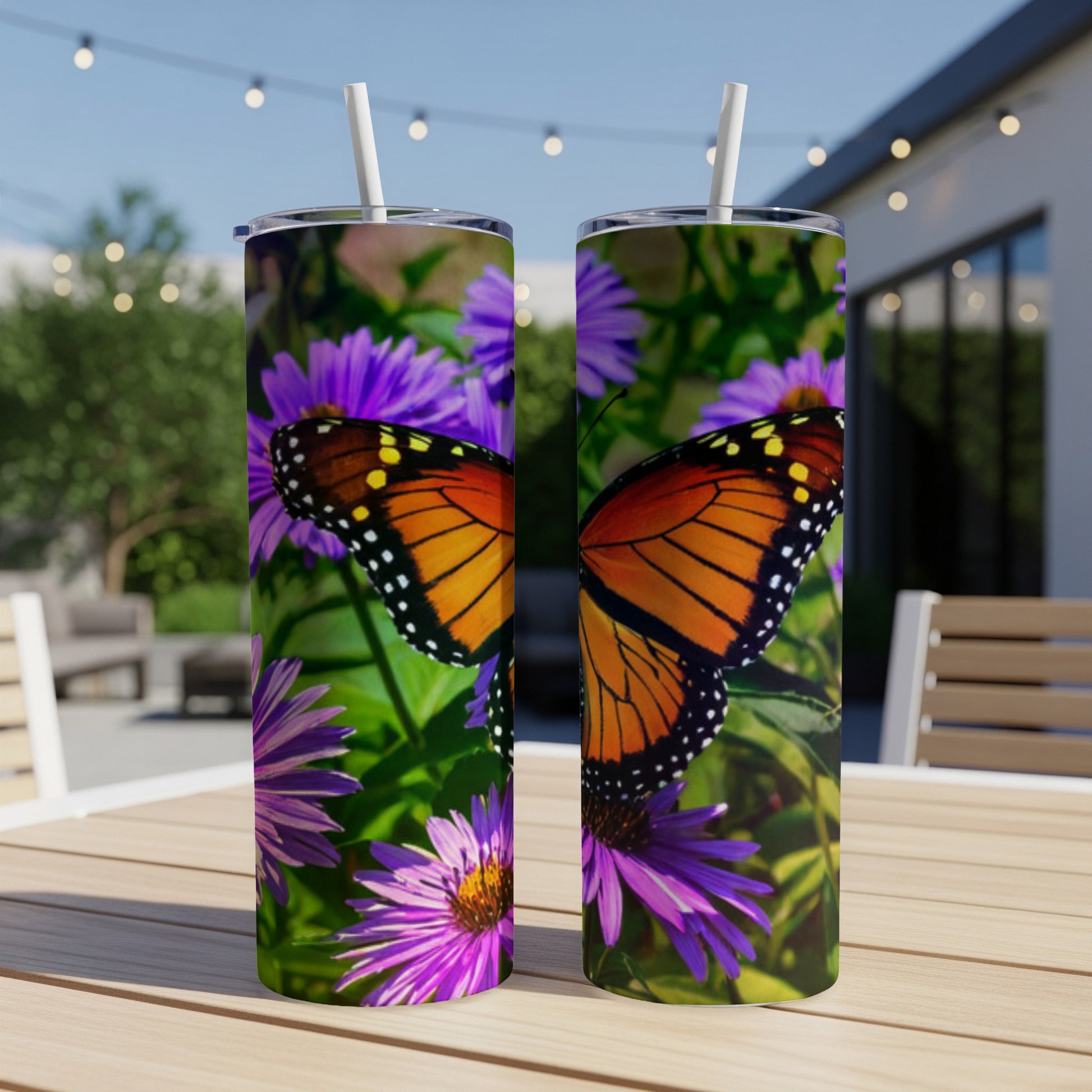 Monarch butterfly and purple asters on two stainless steel tumblers.