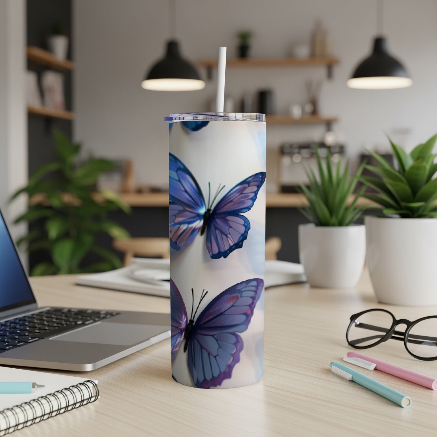 White tumbler with purple butterflies and blue accents, on a desk.