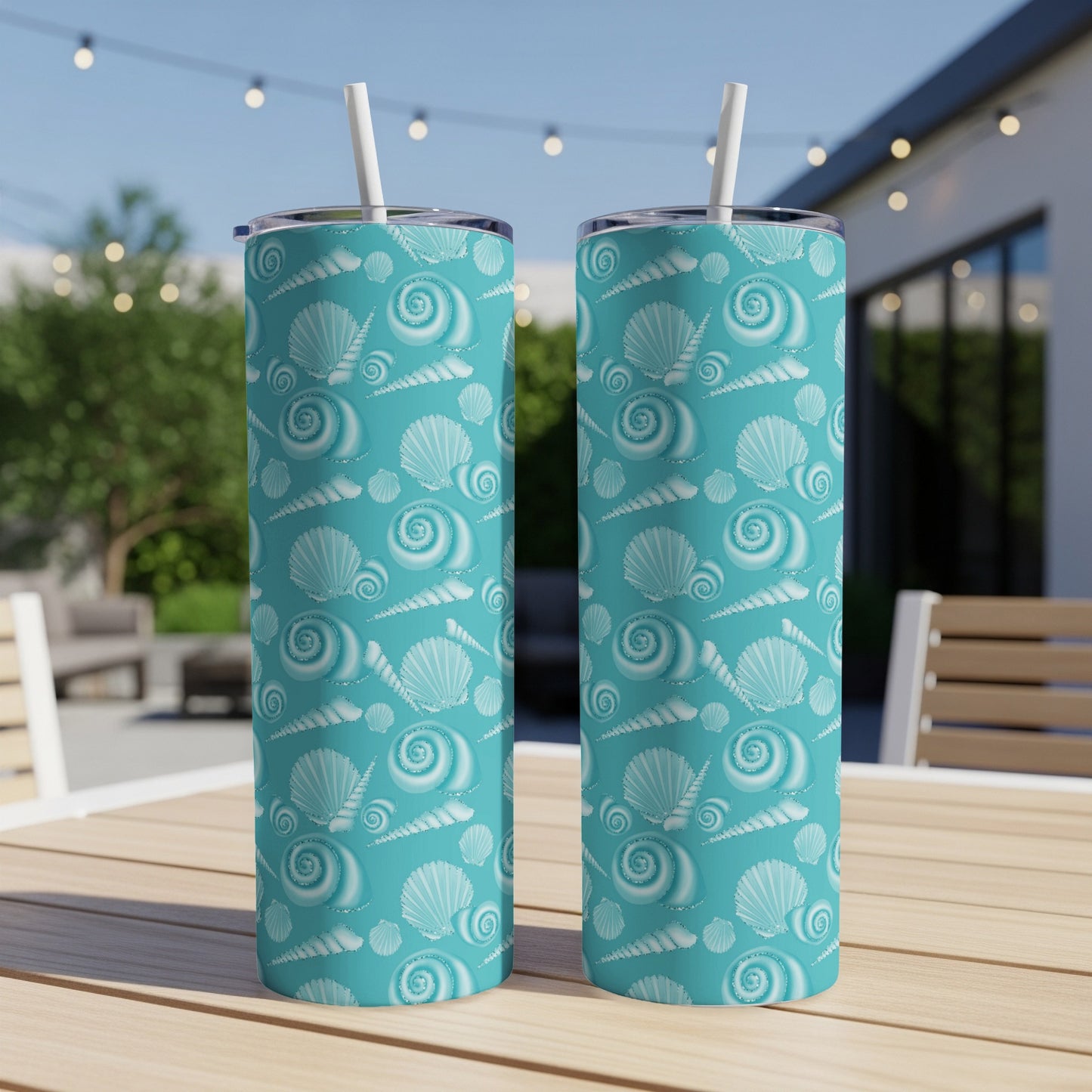 Two turquoise tumblers with seashell pattern on a wooden table.
