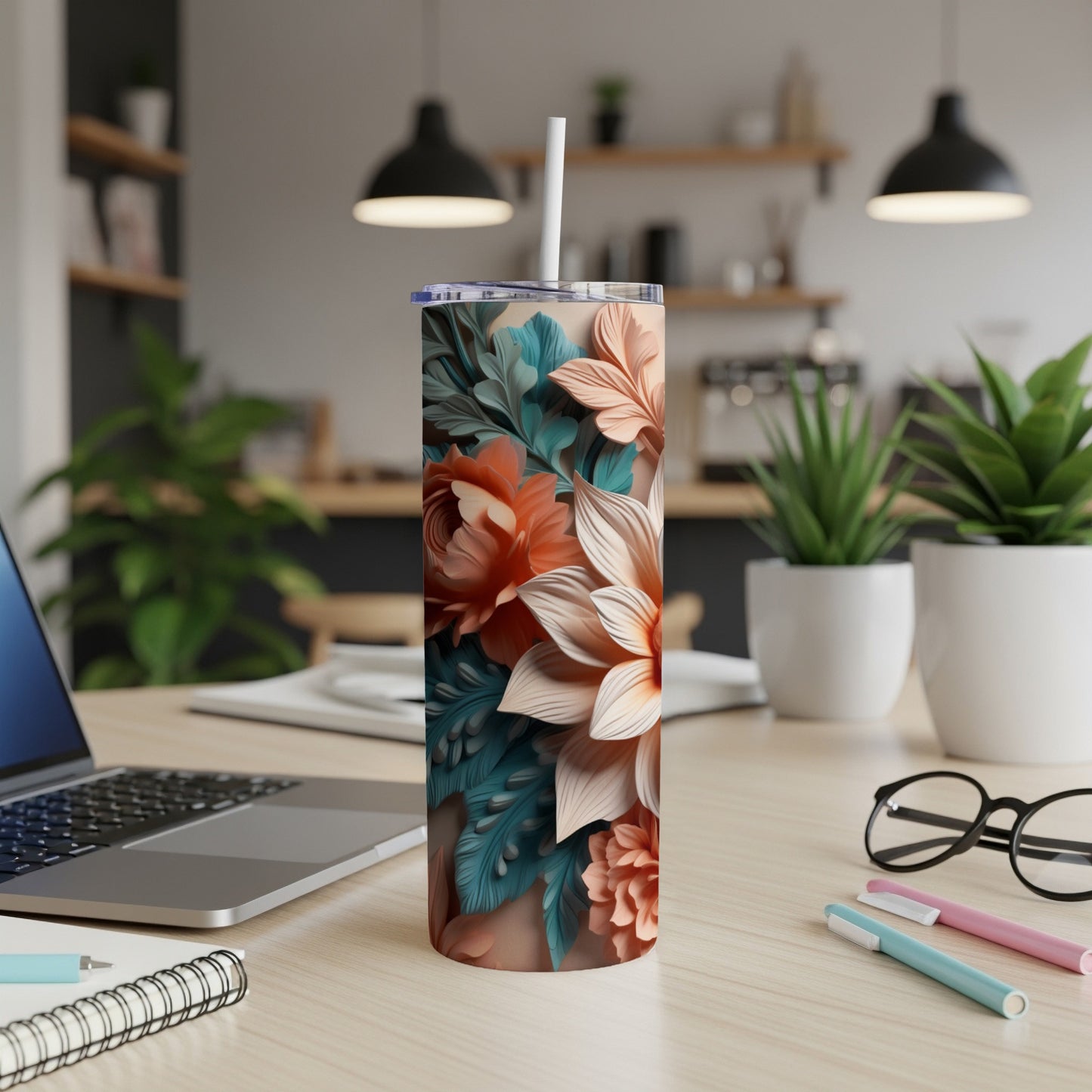 Floral tumbler with straw on a desk next to a laptop.