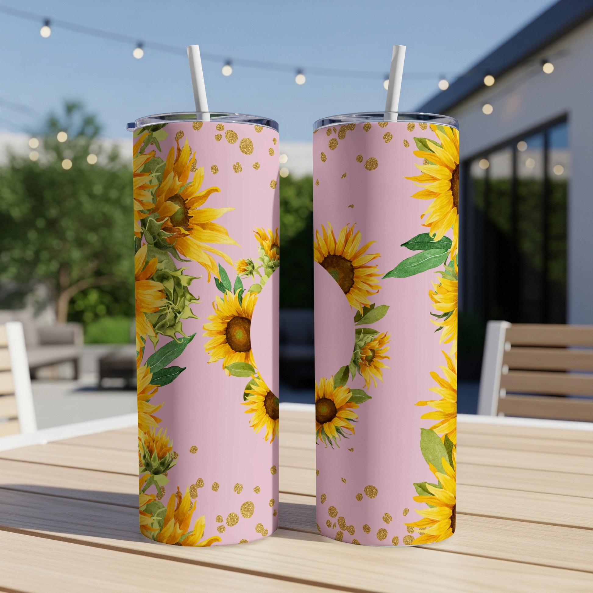 Two pink tumblers with sunflowers and gold polka dots on a table.