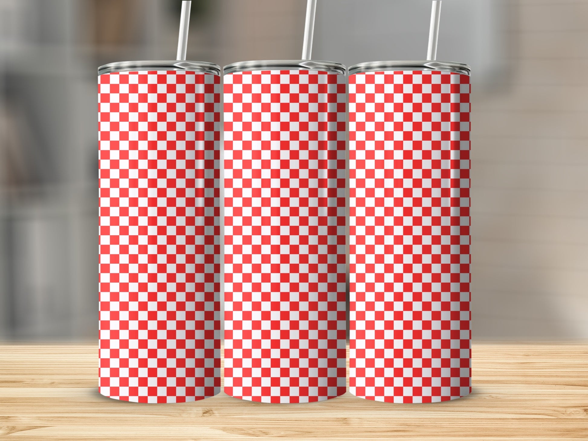 Three tumblers with a red and white checkered pattern sit on a wooden surface.
