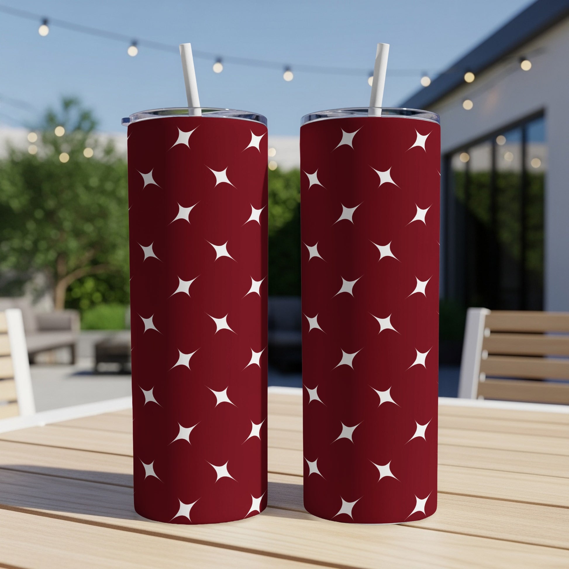 Two maroon tumblers with a white star pattern on a wooden table.