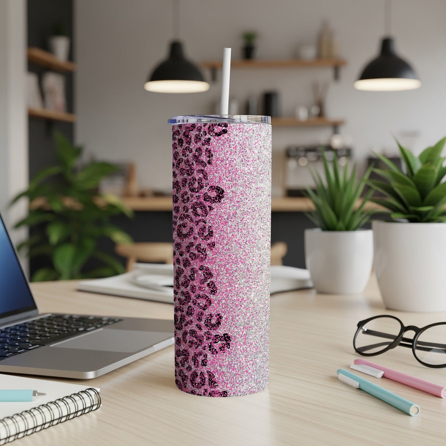 Glittery pink leopard print skinny tumbler with straw on a desk.