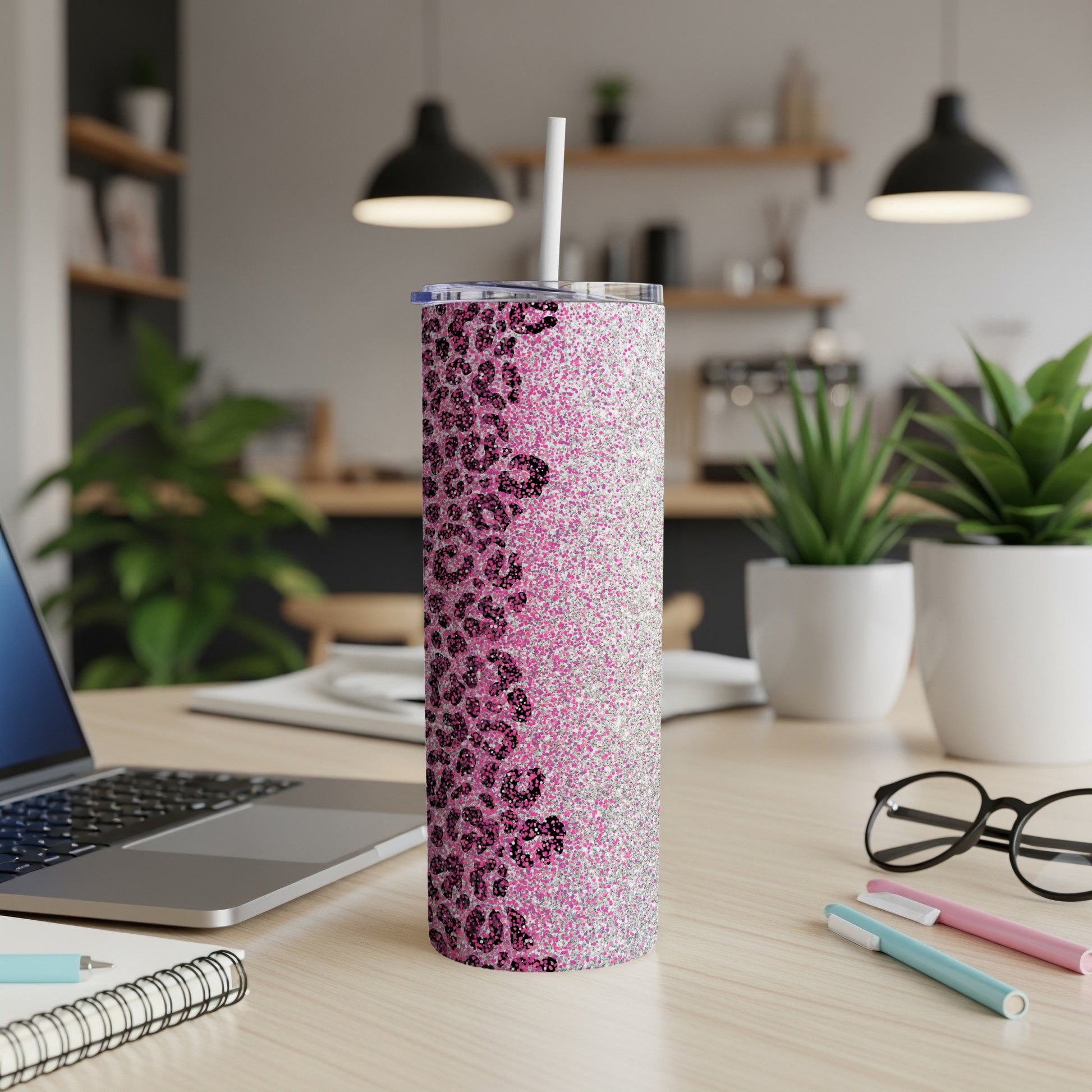 Glittery pink leopard print skinny tumbler with straw on a desk.