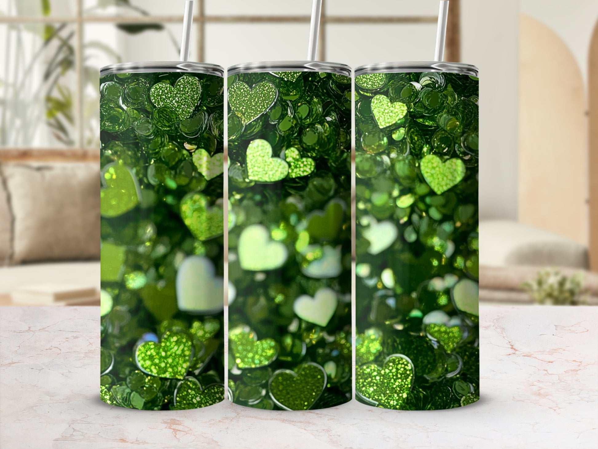 Green glitter heart tumbler with straw on marble surface.