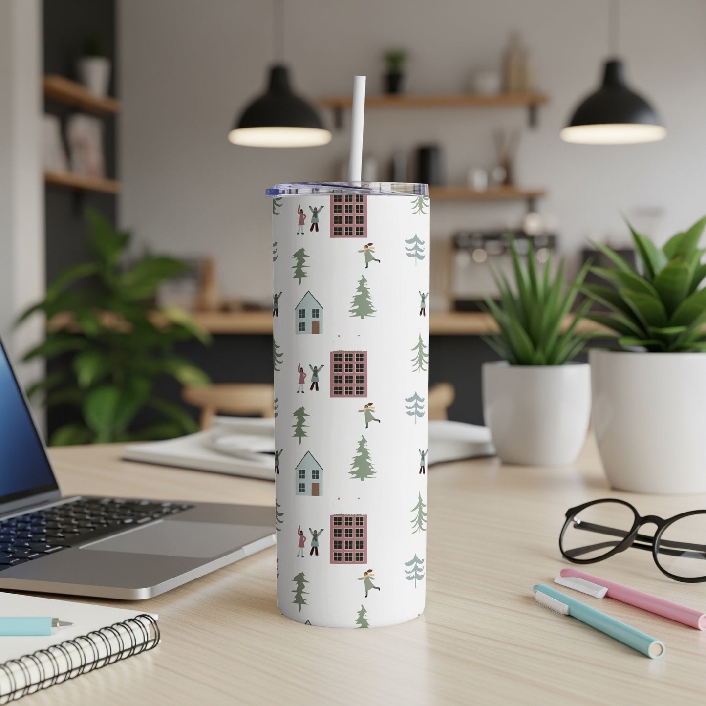 White tumbler with colorful winter village and tree pattern, straw inserted.
