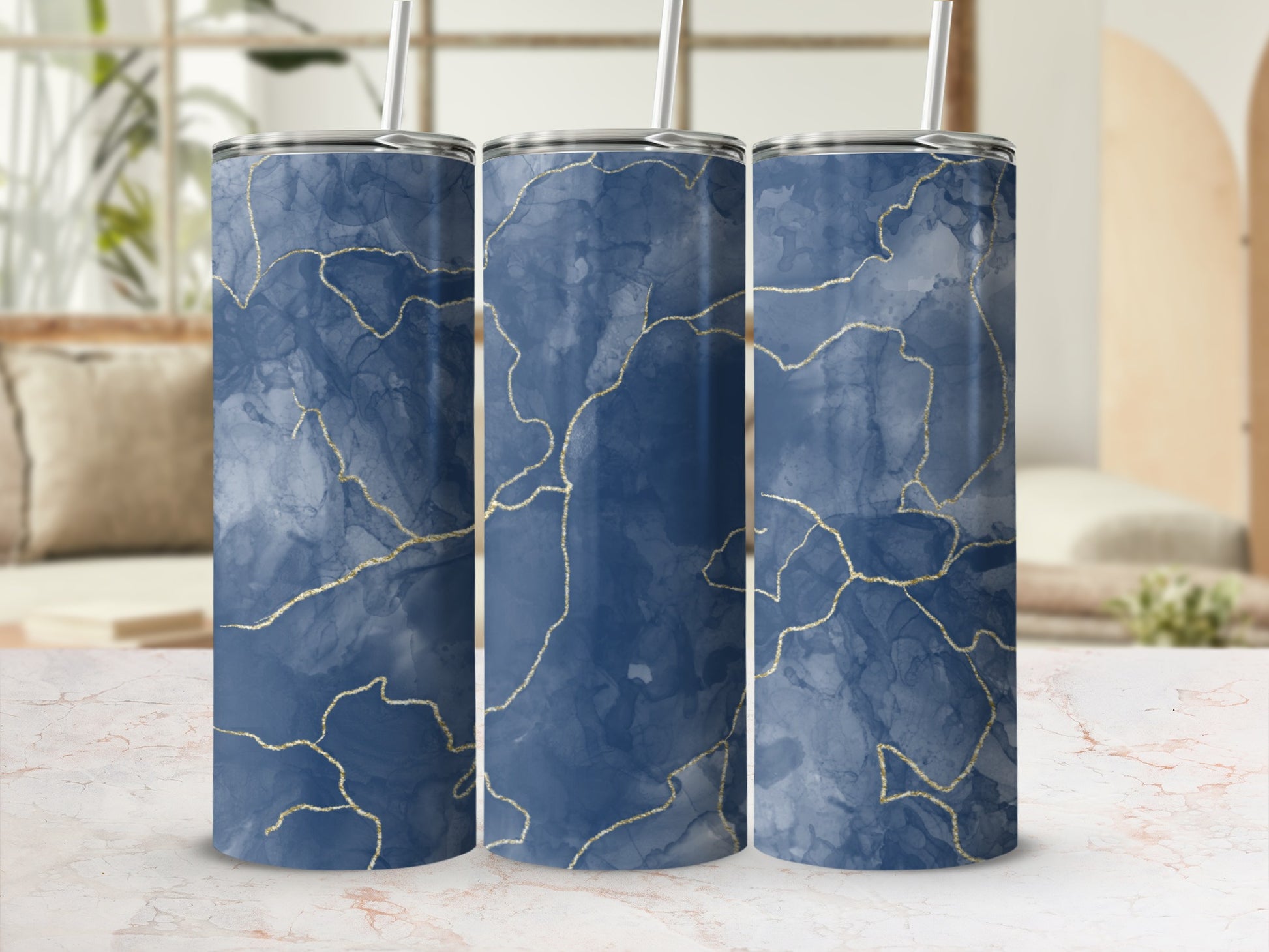 Three blue marble tumblers with gold veining and straws.