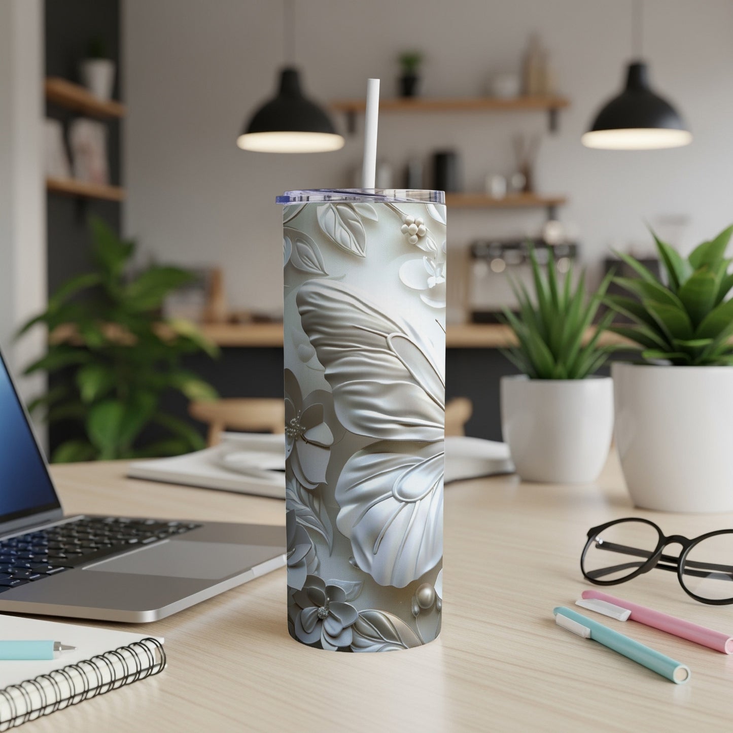 White floral embossed tumbler with butterfly design and straw on a desk.