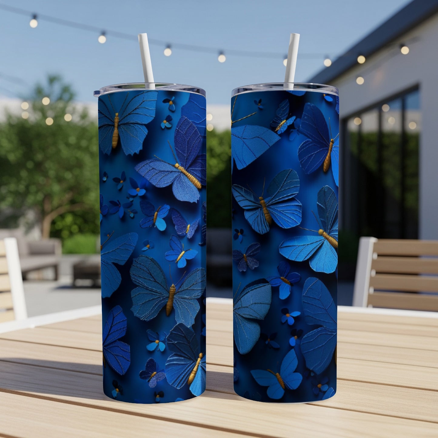 Two blue butterfly patterned tumblers with straws on a wooden table.