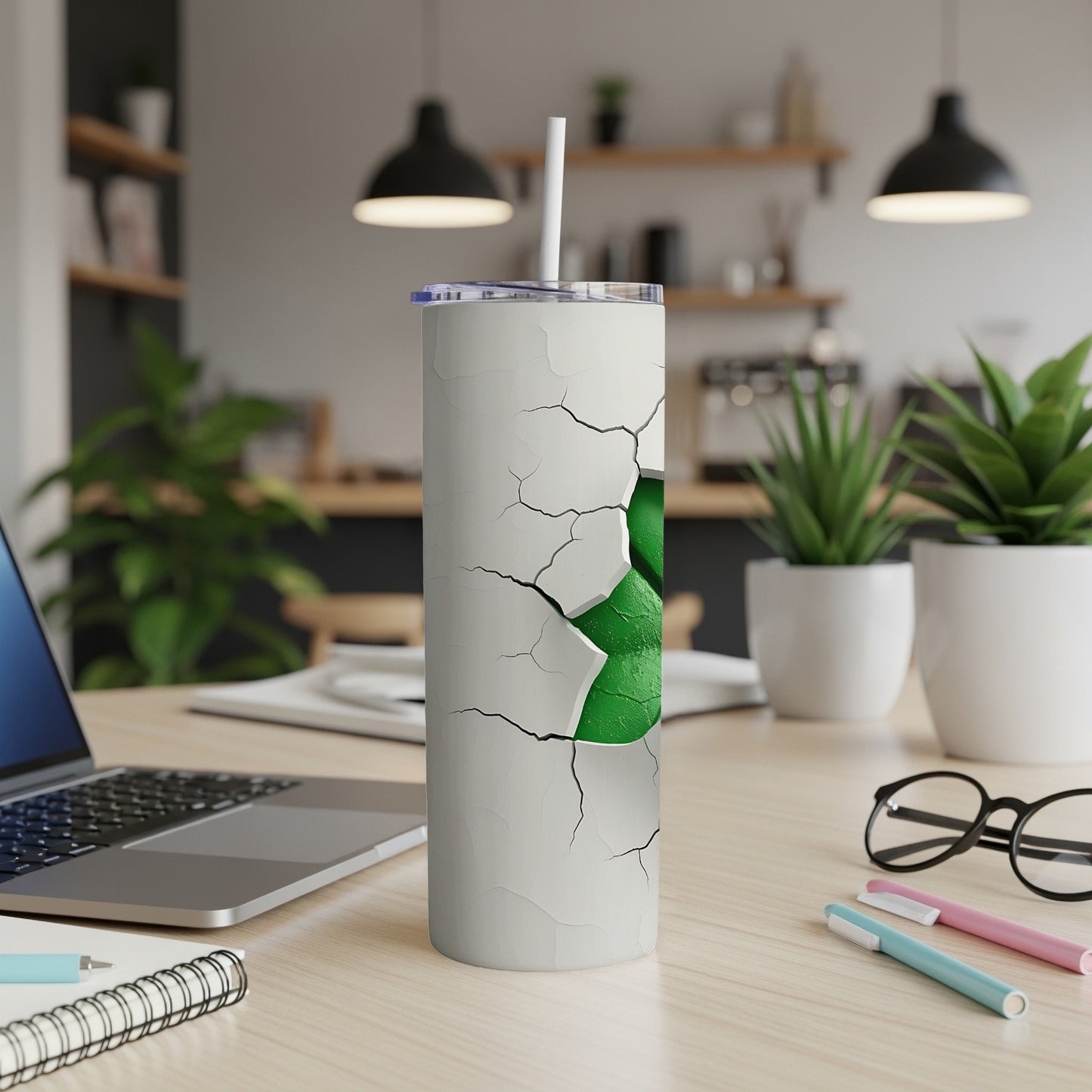 White tumbler with cracked effect revealing green inside, on a desk.