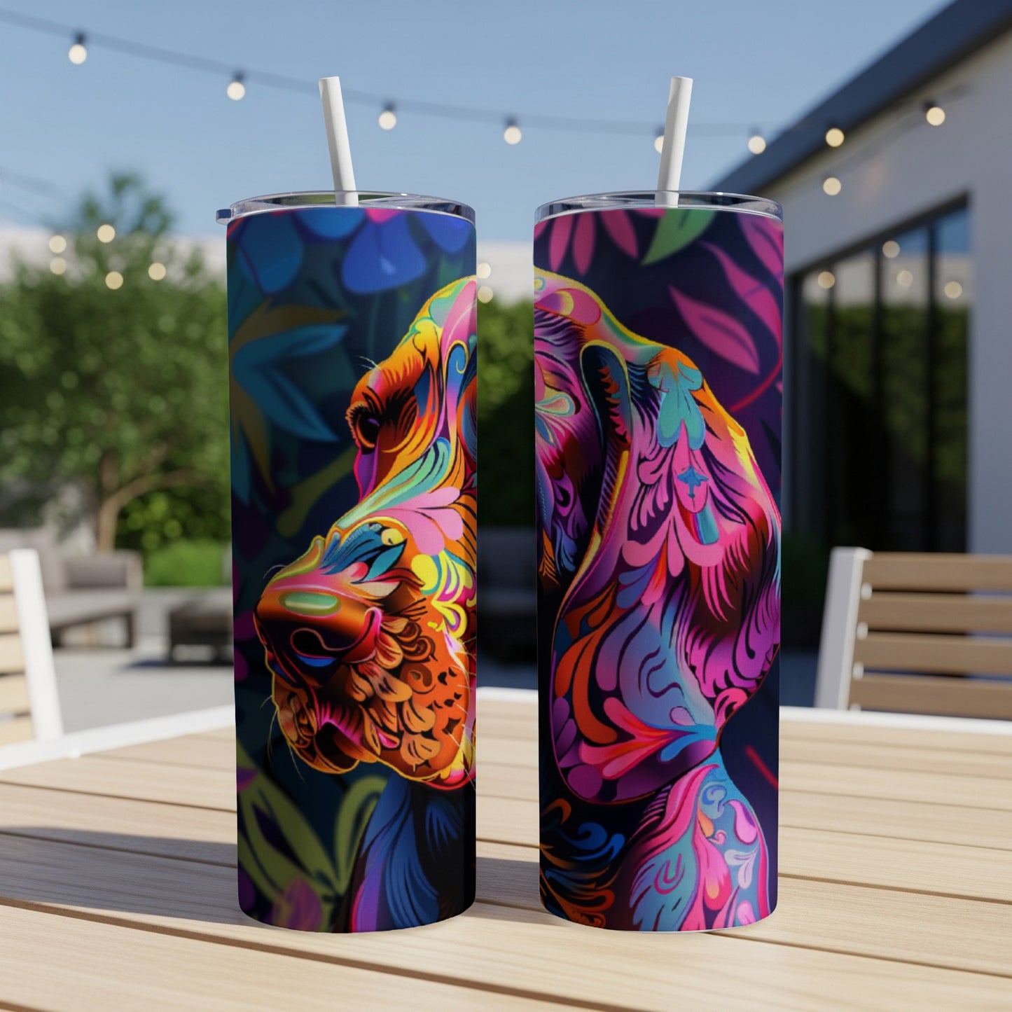 Two colorful artistic dog portraits on tumblers with straw, set outdoors.