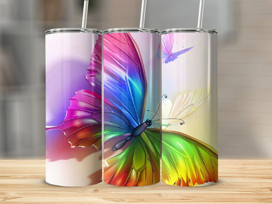 Three tumblers with colorful butterfly designs and straws.