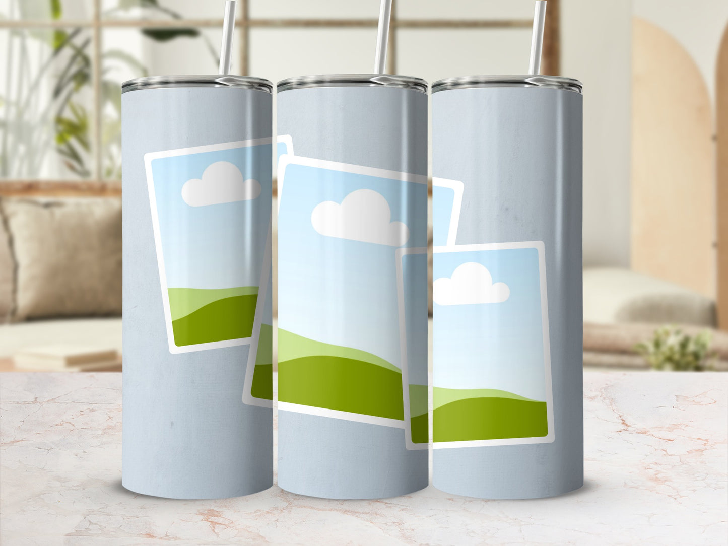 Three light blue tumblers with straw showing a stylized landscape design.