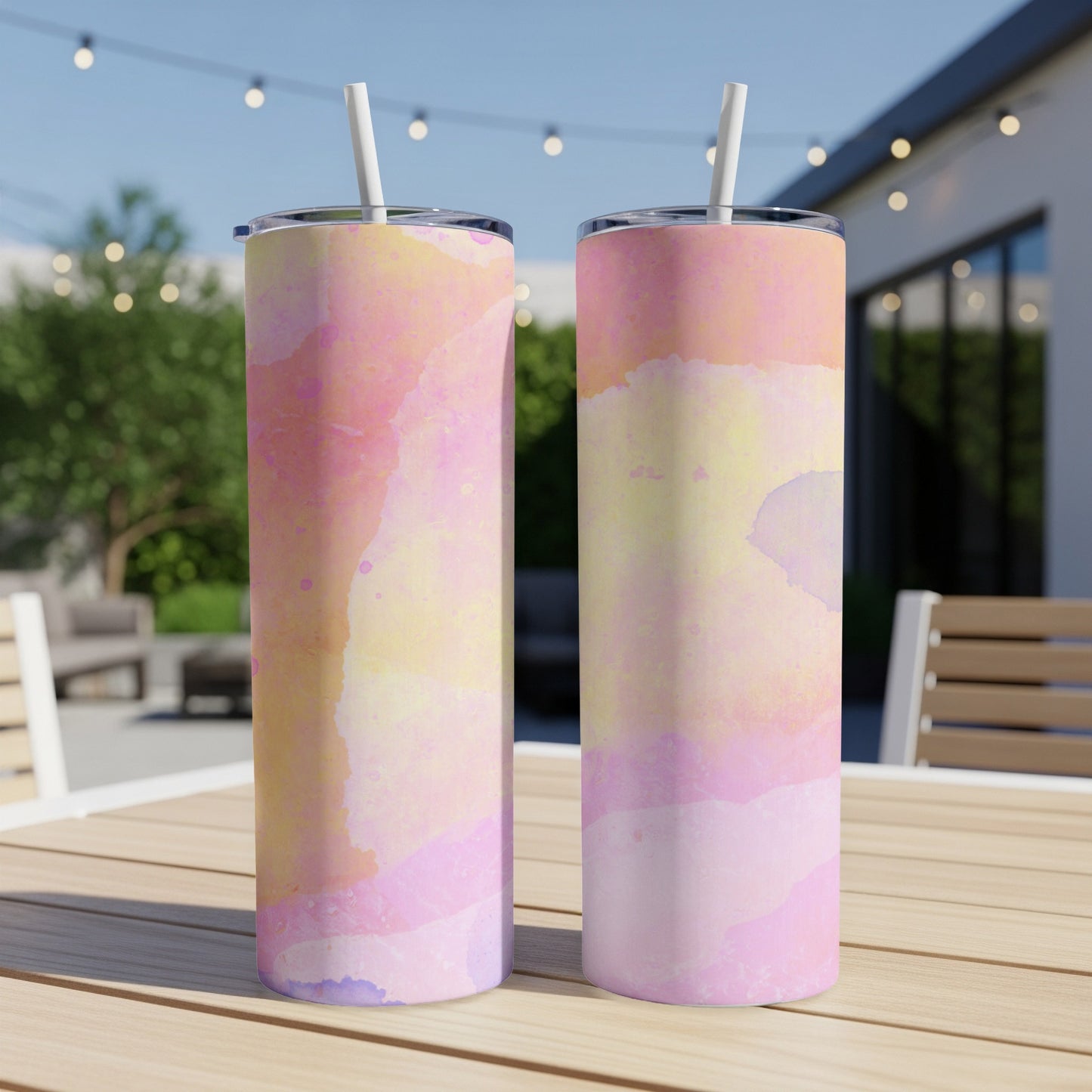 Two tumblers with a pink and yellow watercolor pattern on a table.