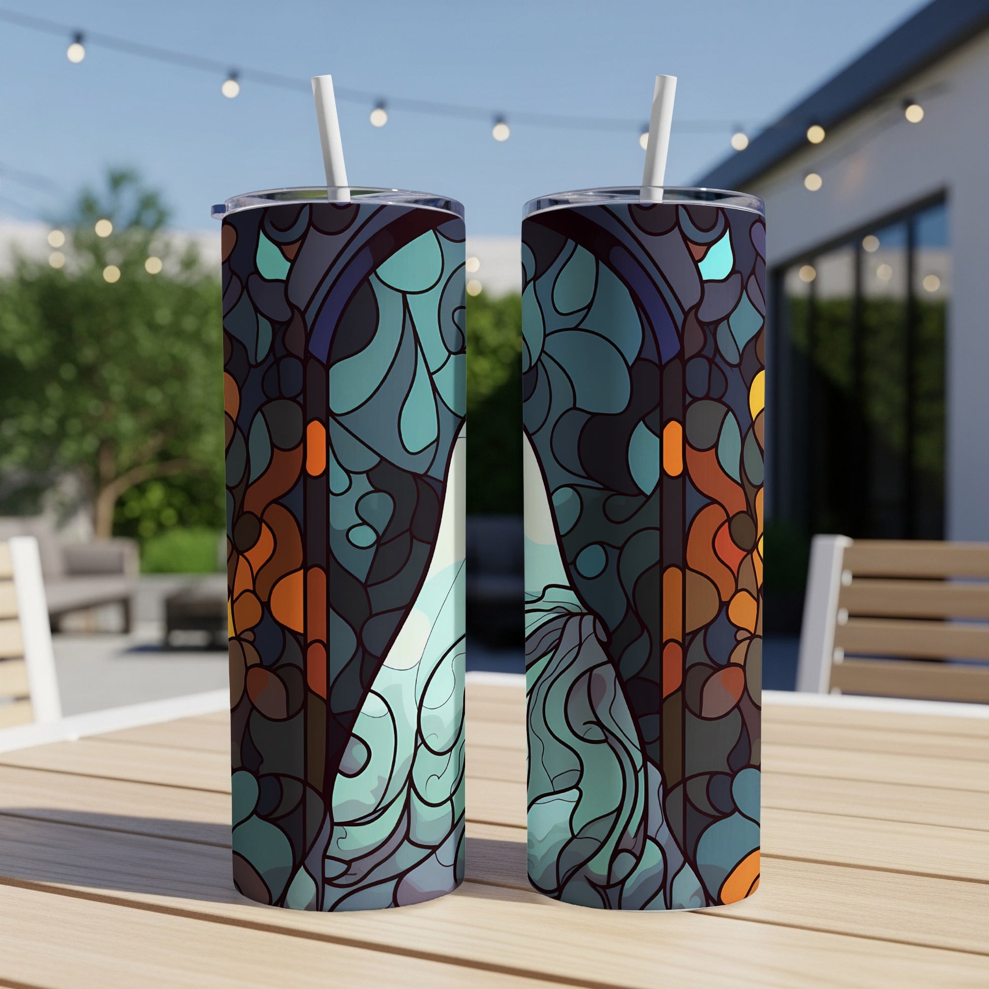 Two tumblers with a blue and orange stained glass pattern sit on a wooden table outdoors.
