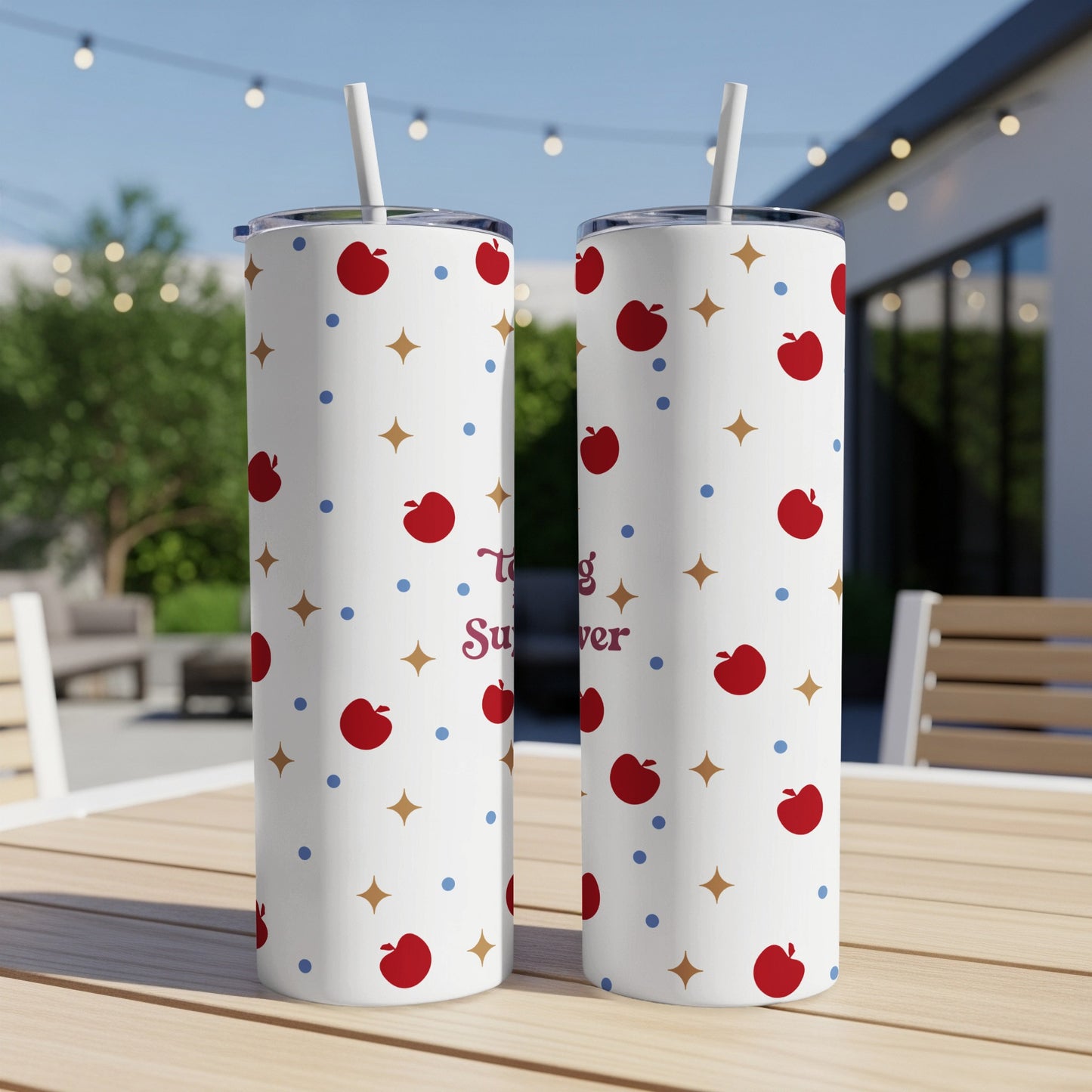 Two tumblers with a red apple and blue star pattern, on a wooden table.