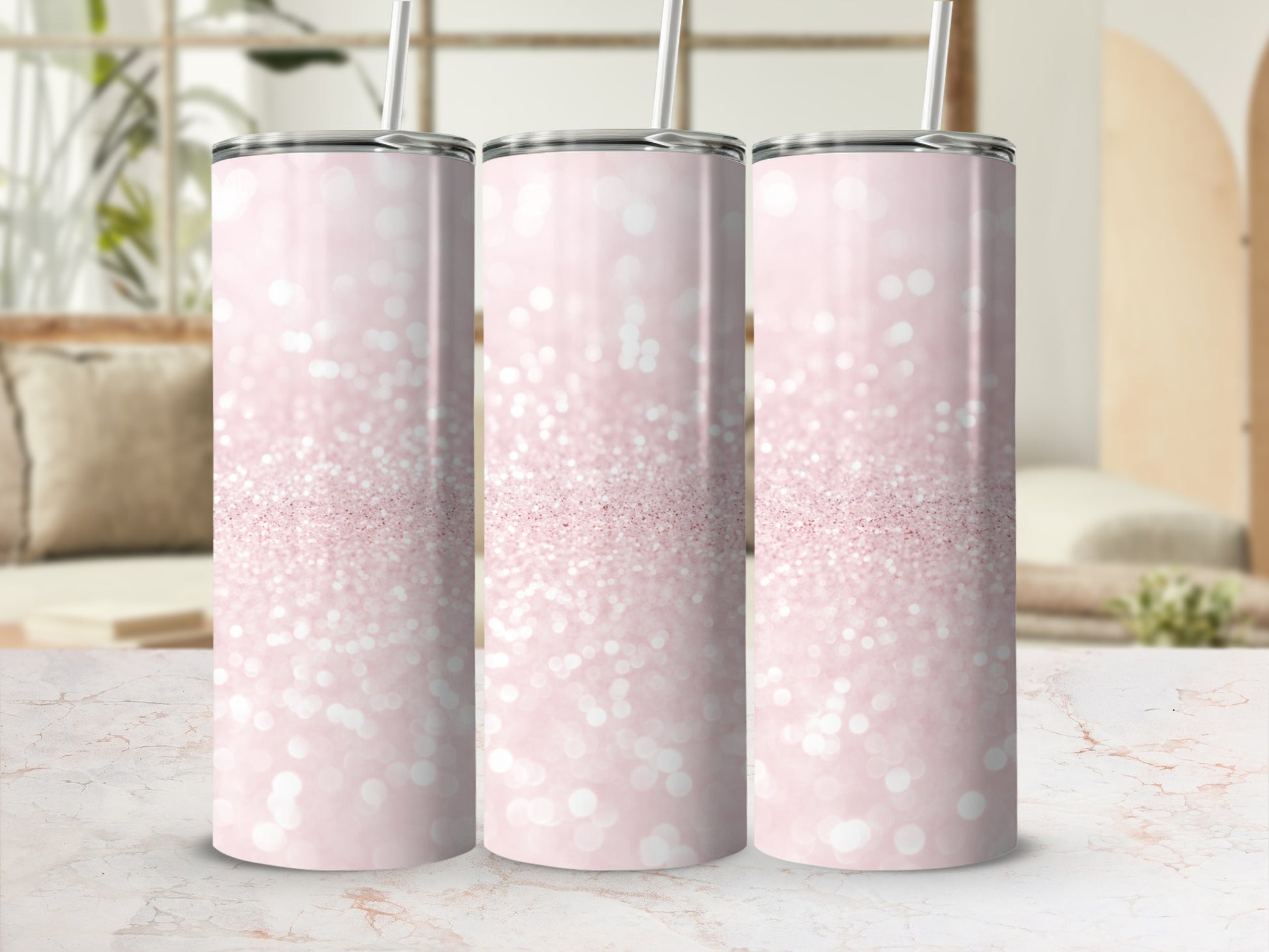 Three pink glitter tumblers with straws on a marble surface.