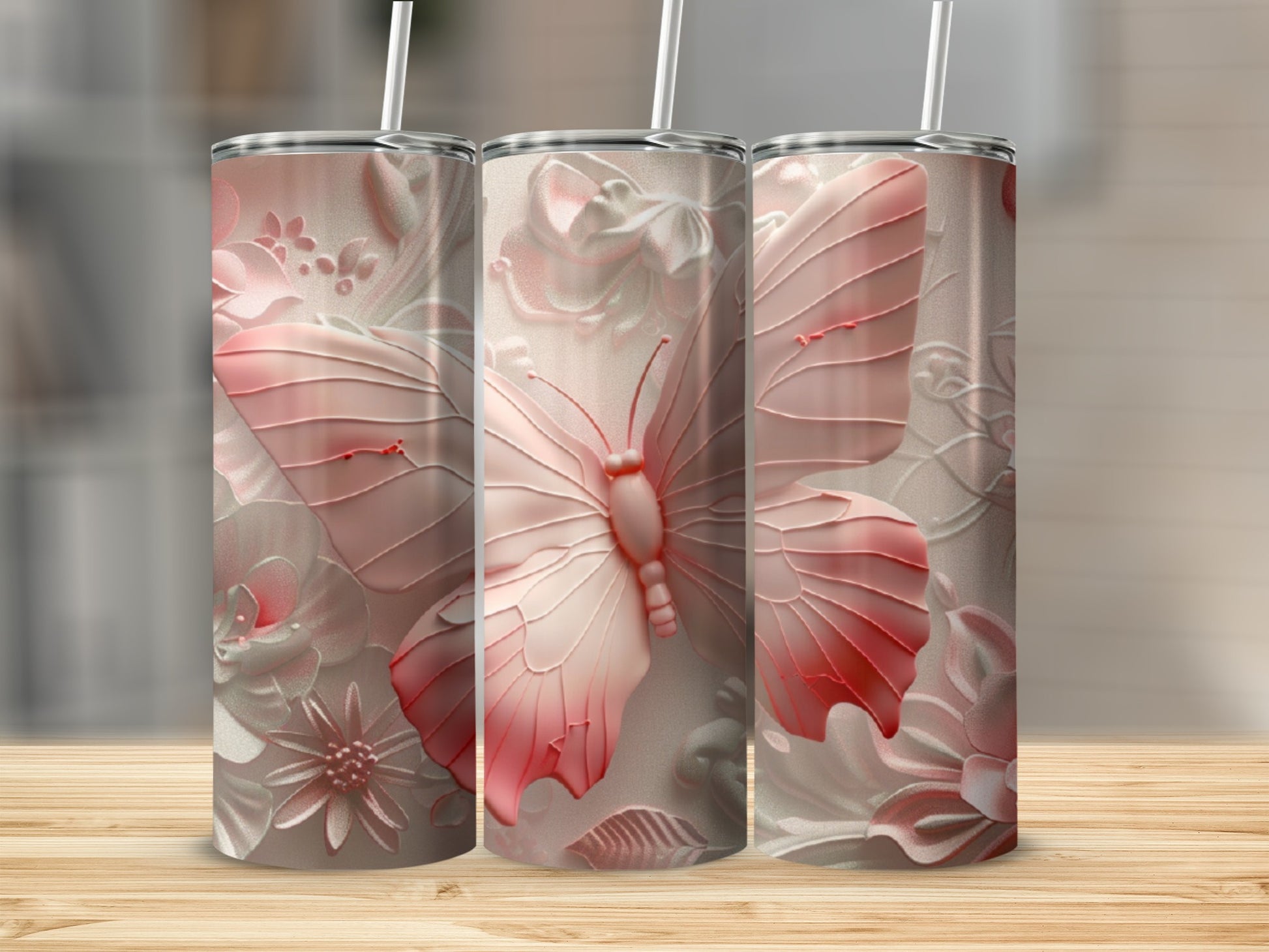 Pink butterfly and floral embossed tumblers on a wooden surface.