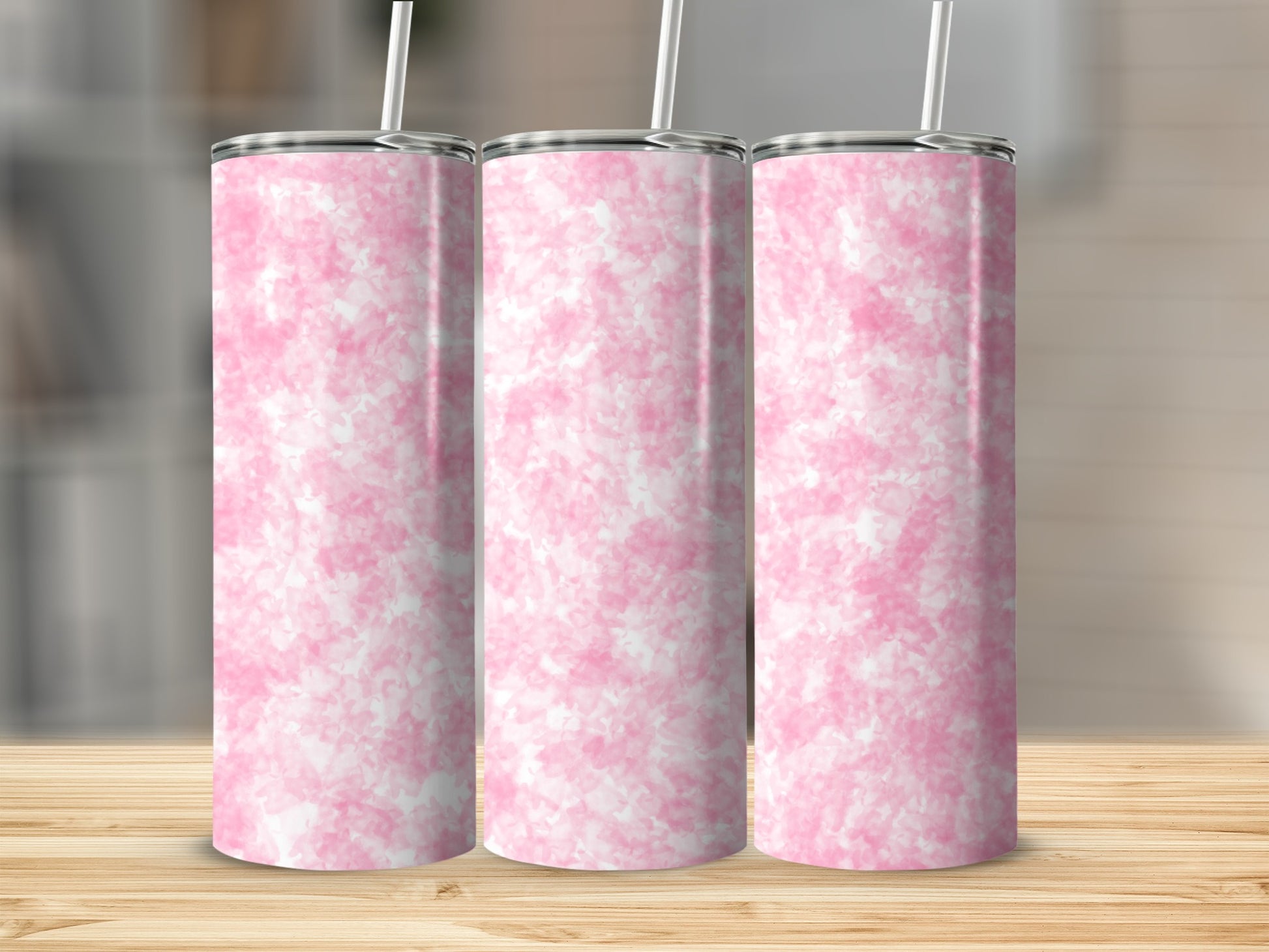 Three tall pink marbled tumblers with straws on a wooden surface.