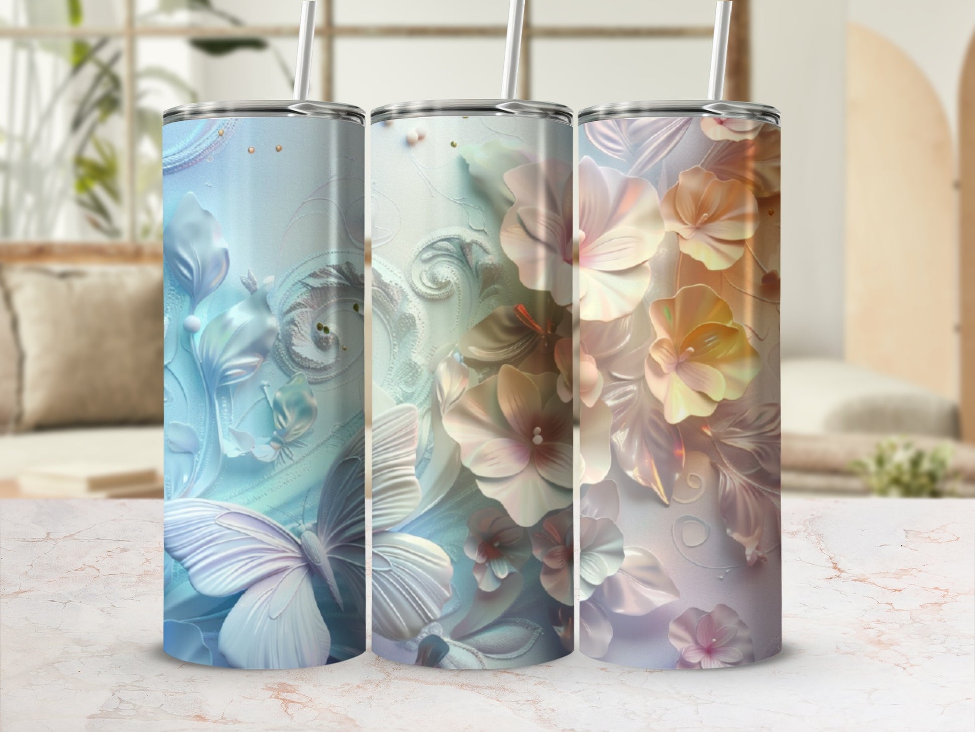 Three floral and butterfly patterned tumblers in pastel colors on a marbled surface.