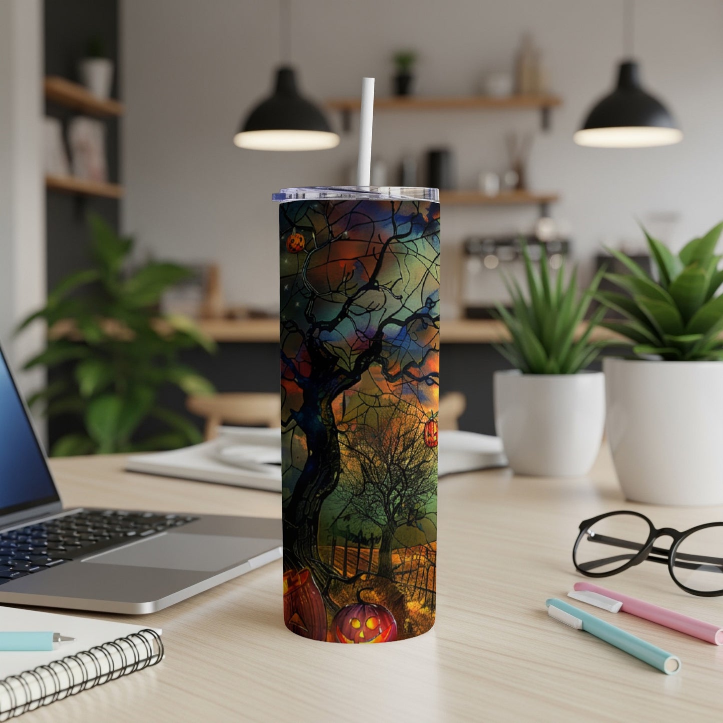 Halloween-themed tumbler with spooky tree, pumpkin, and bats on a desk.