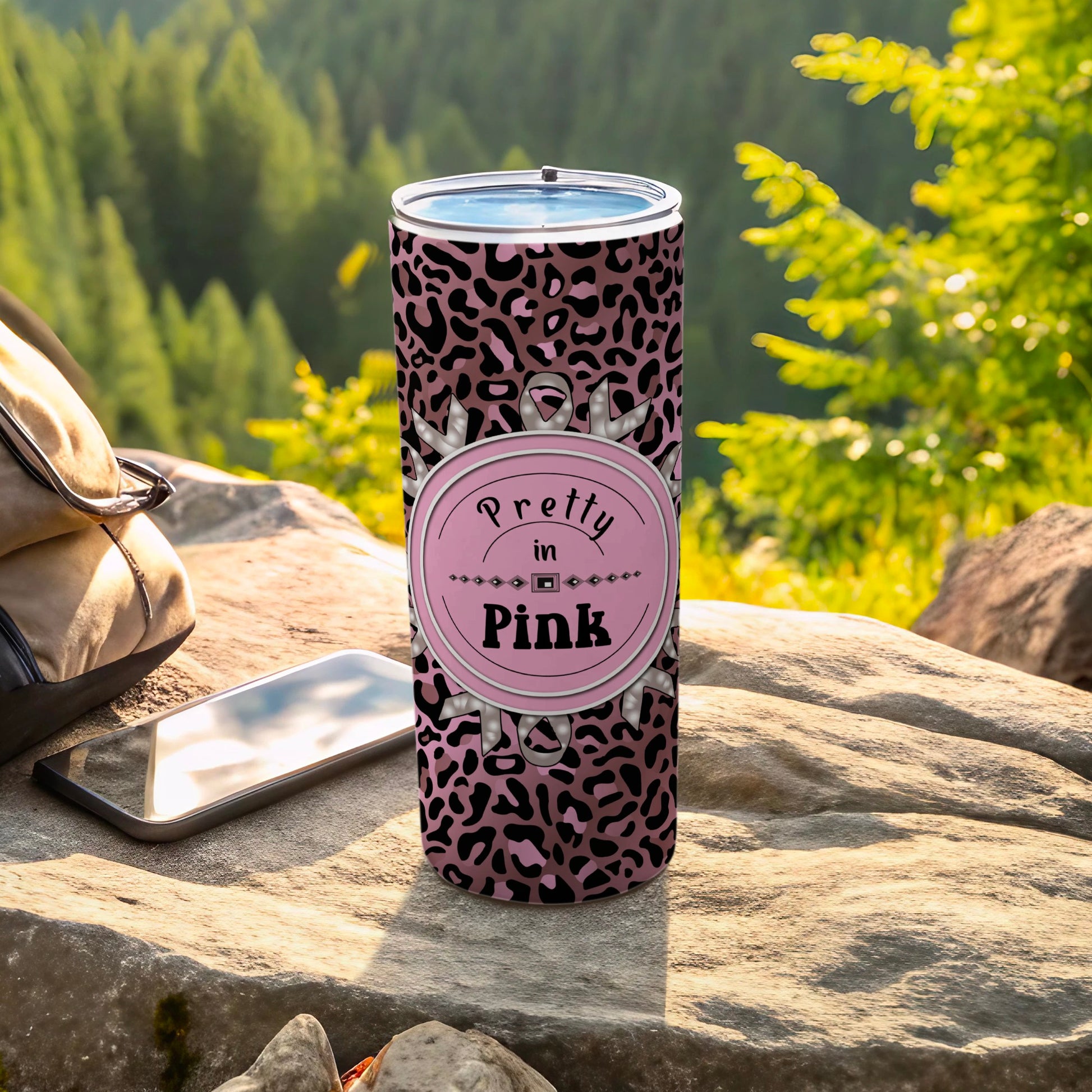 Pink leopard print tumbler with "Pretty in Pink" text, on rocky surface outdoors.