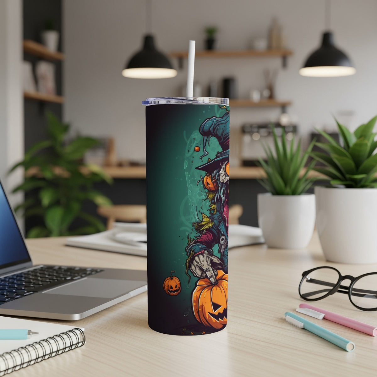 Tall tumbler with a cartoon scarecrow holding pumpkins against a teal background.