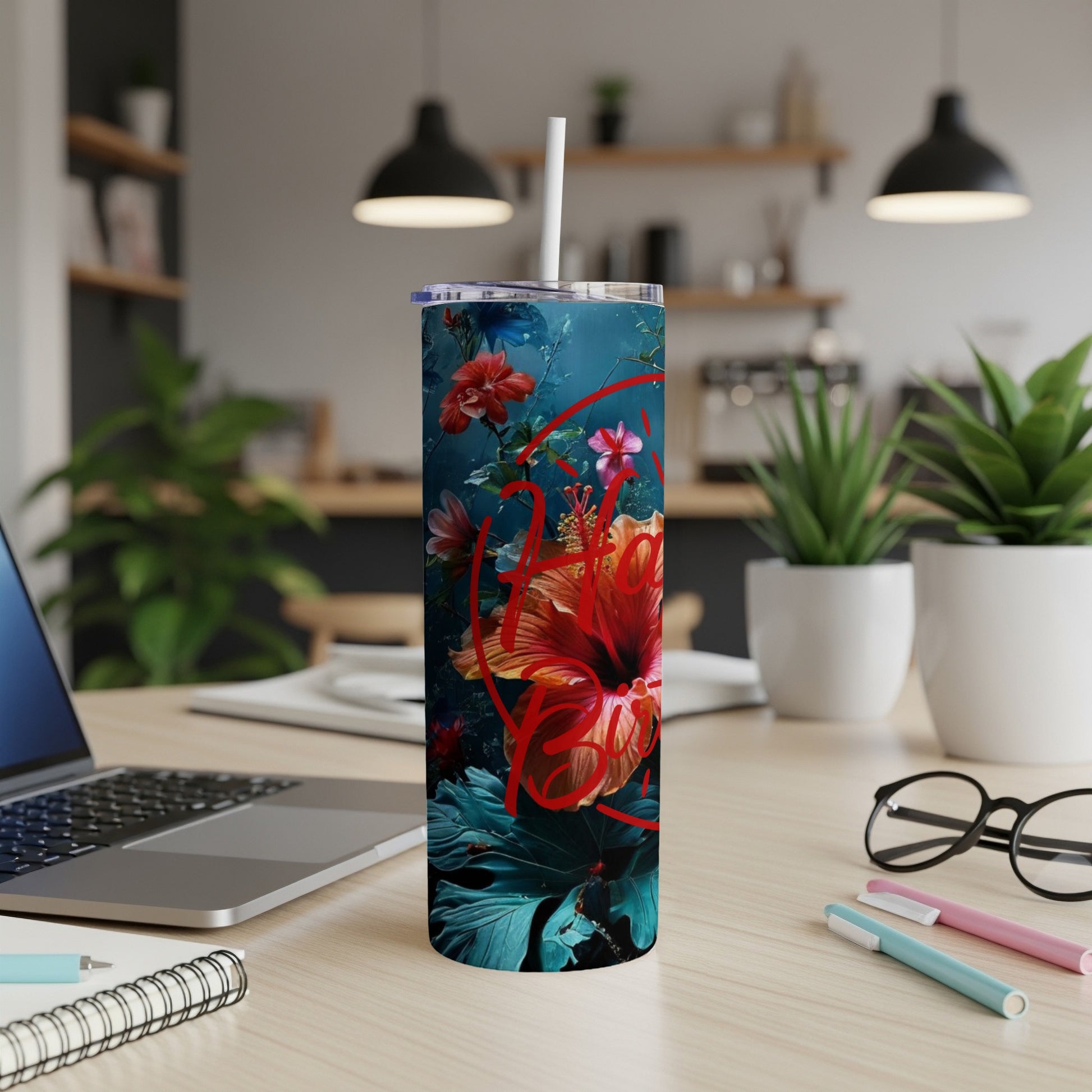 Floral hibiscus tumbler with straw on a desk.