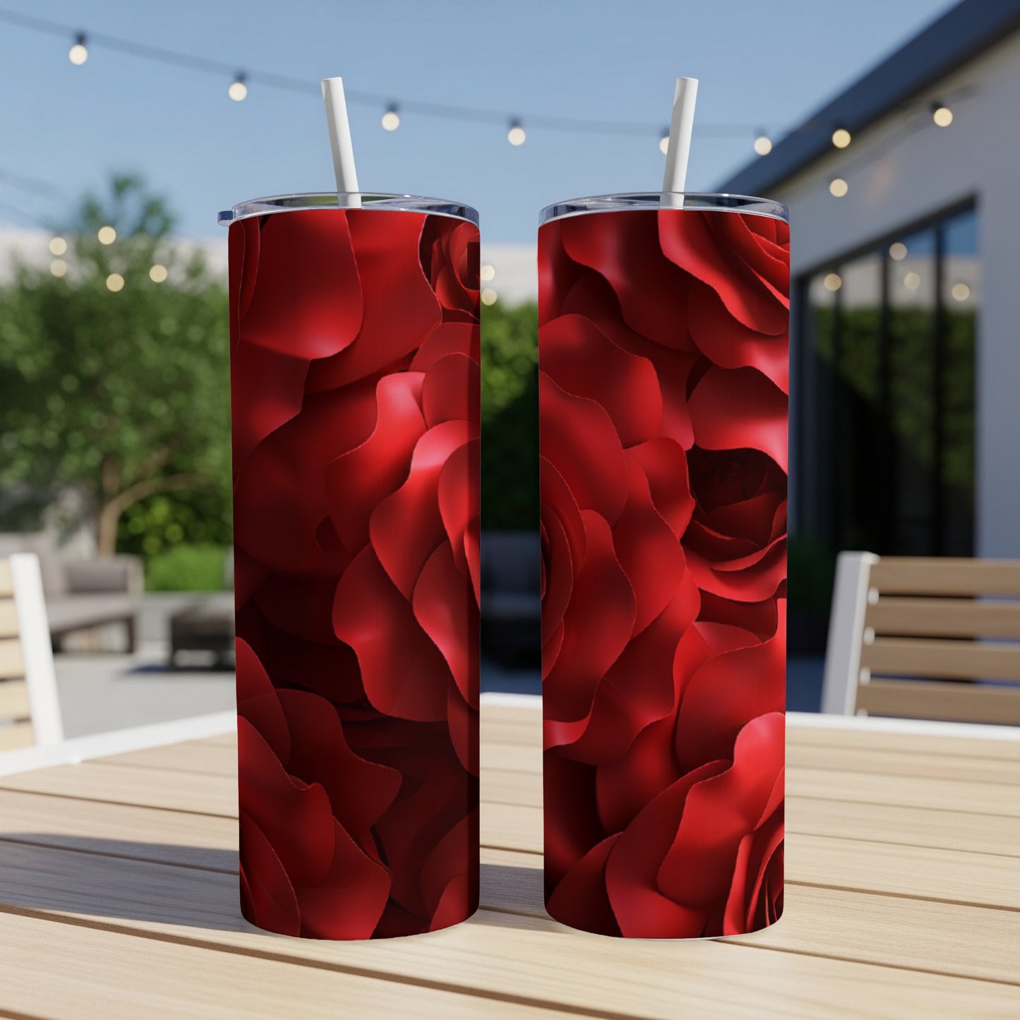 Two red rose pattern tumblers with straws on a wooden table.
