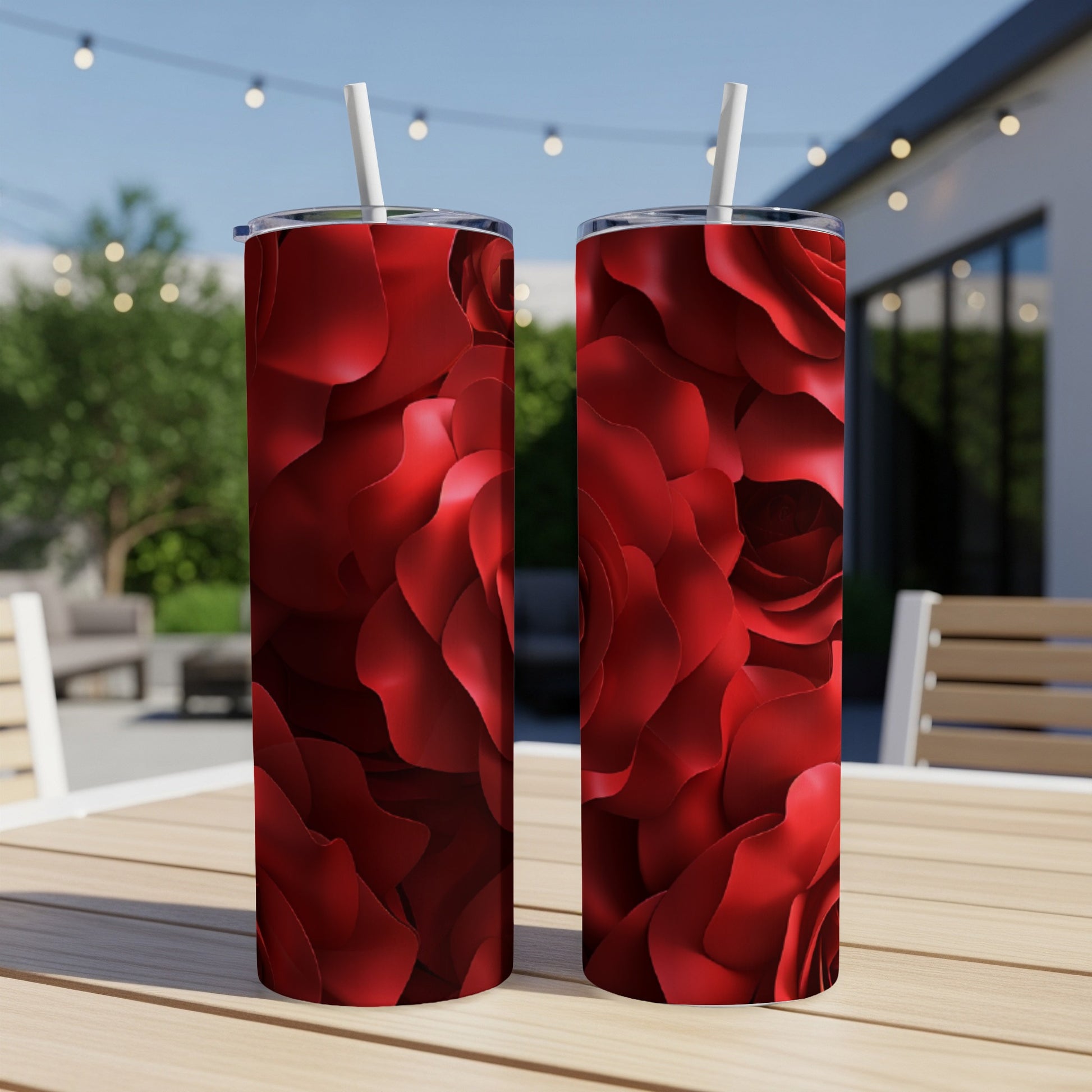 Two red rose pattern tumblers with straws on a wooden table.