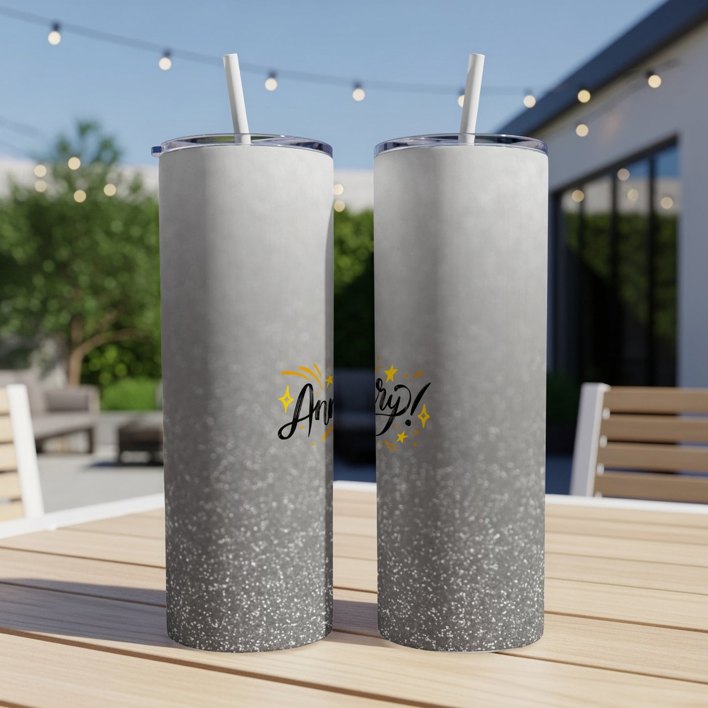 Two shimmering silver tumblers with "Anniversary!" text stand on a table.