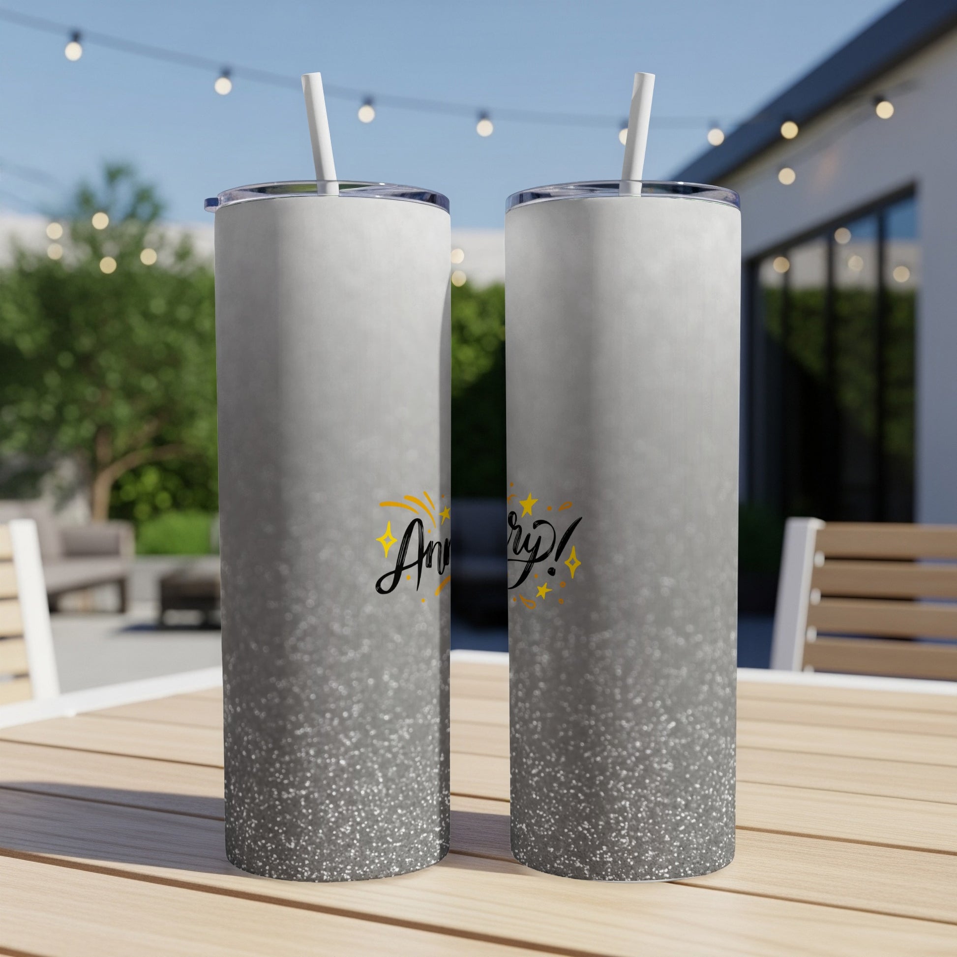 Two shimmering silver tumblers with "Anniversary!" text stand on a table.